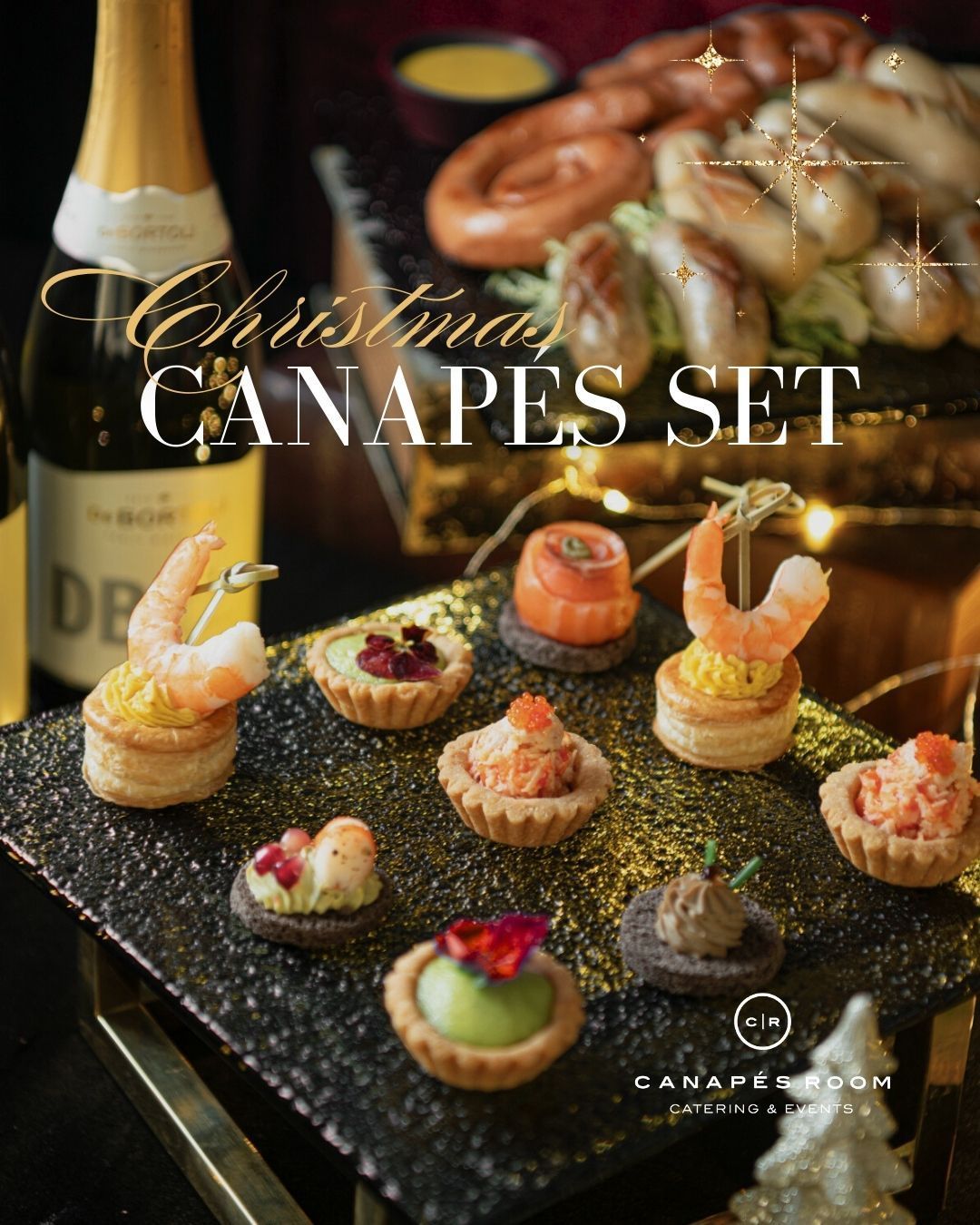 Christmas canapés set on a dark platter with a bottle of champagne in the background.