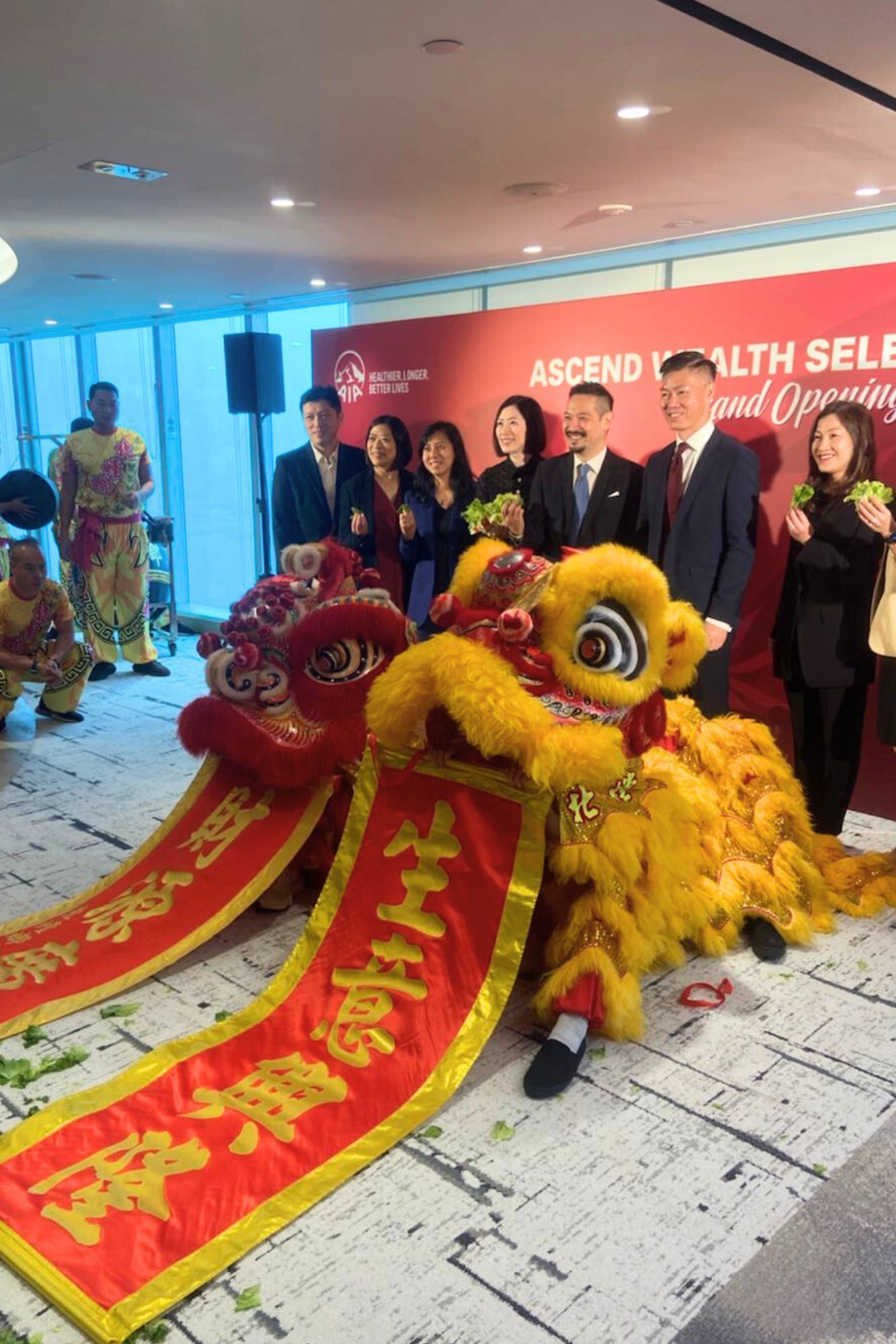 Lion dancers with red and gold banners celebrate with a group of people.