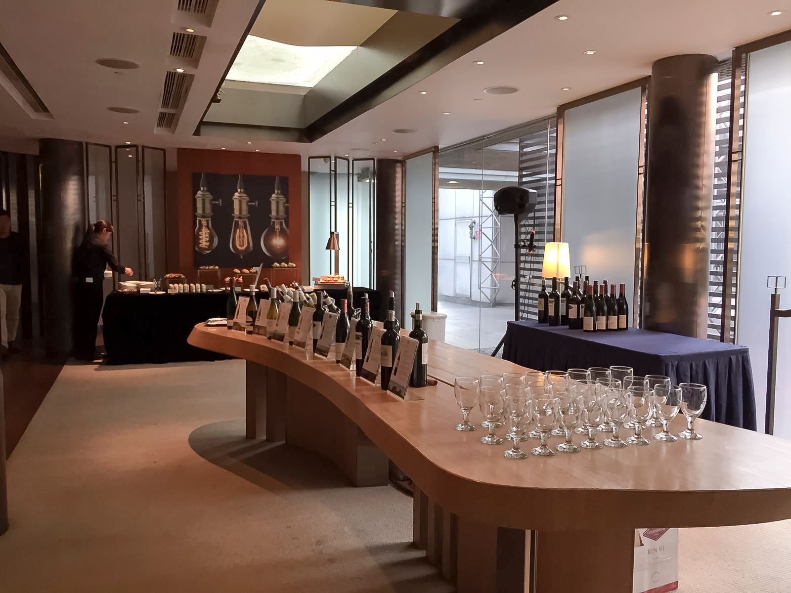 Wine tasting setup with bottles, glasses, and food tables in a modern room.