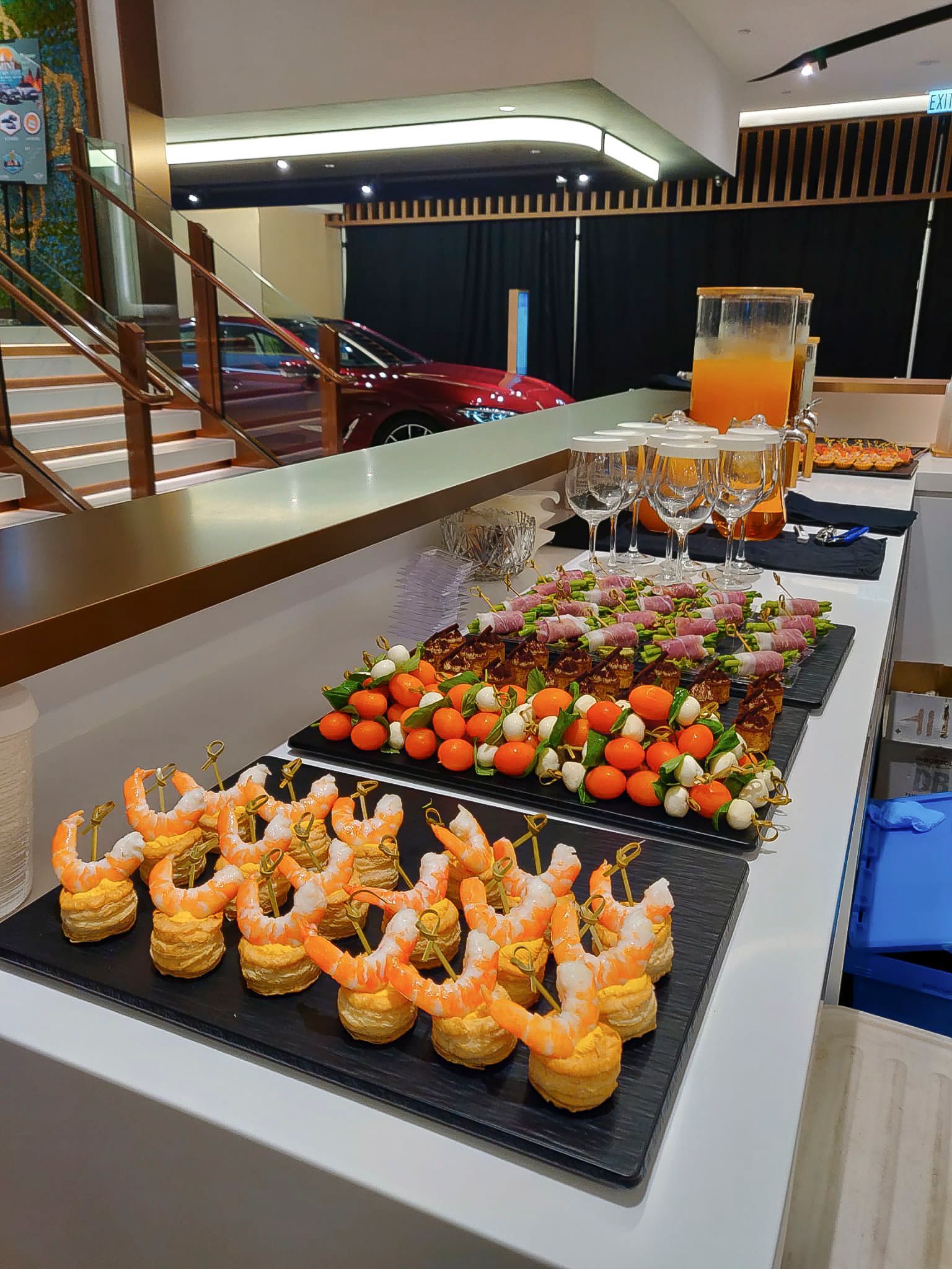 Buffet with shrimp appetizers, fruit, and drinks, set up for an event with a car in the background.