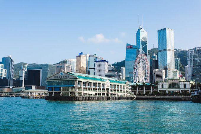香港城市景觀，摩天大樓、摩天輪和碼頭在藍天水面的襯托下顯得格外醒目。