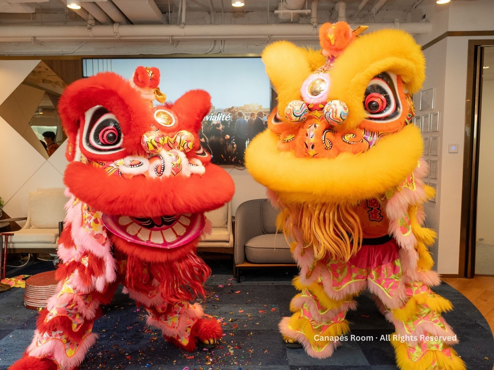 Red and yellow lion dance costumes face each other on a blue carpet.