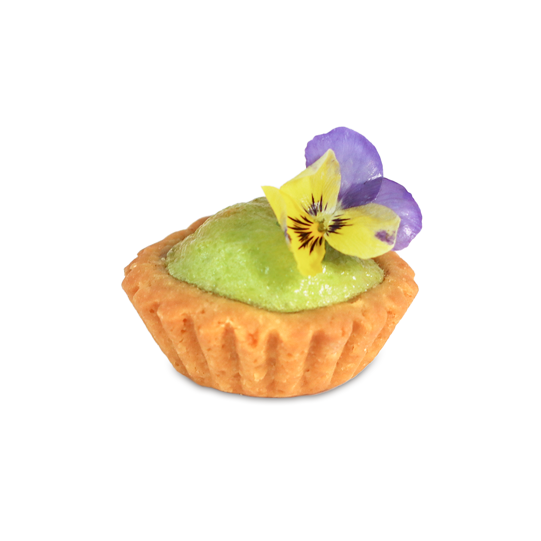 Mini tart filled with green mousse, topped with yellow and purple edible flowers.
