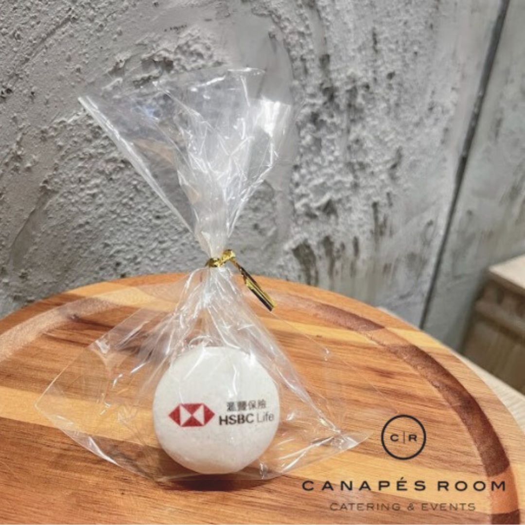 White ball with HSBC Life logo, wrapped in clear plastic, tied with gold string, on a wooden plate.
