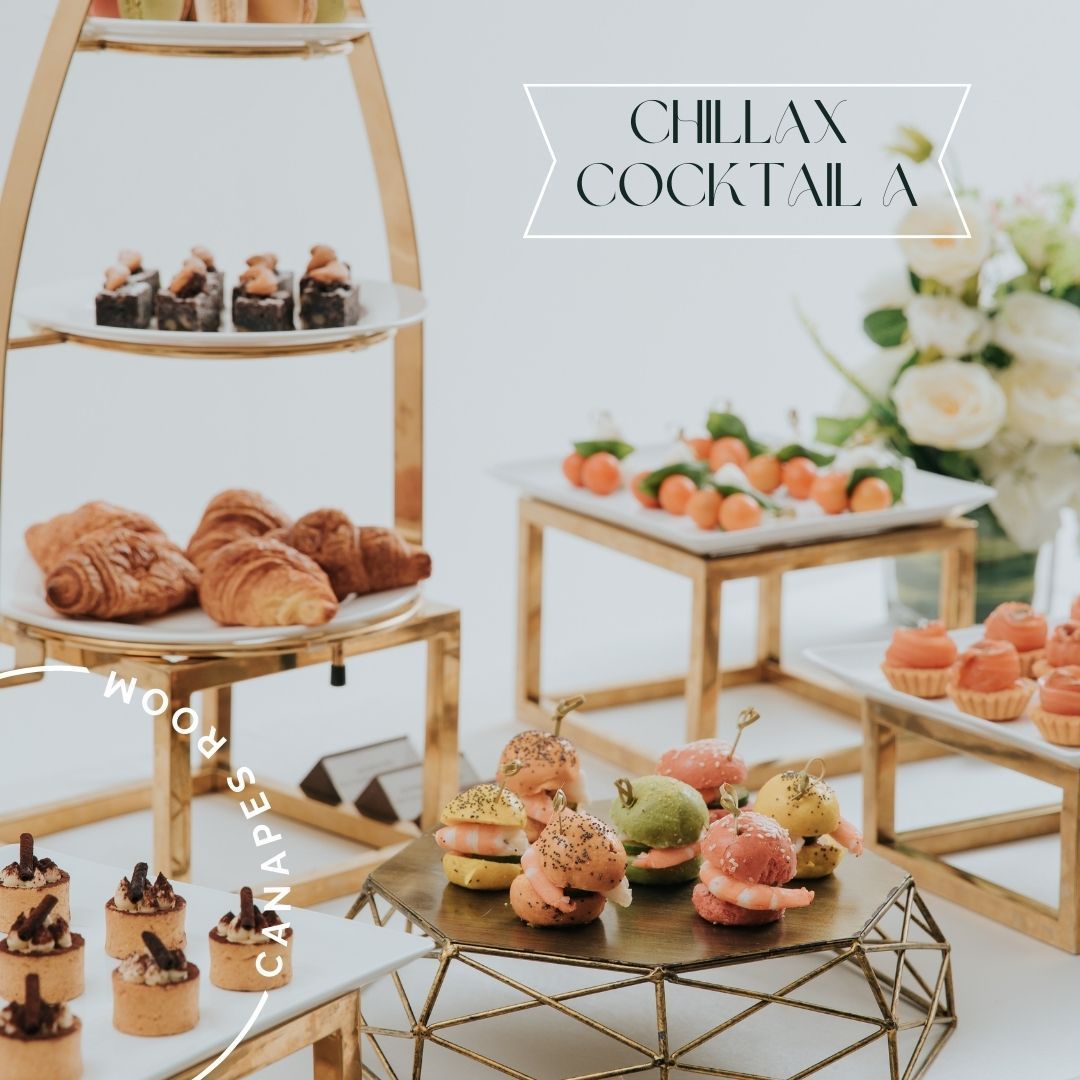 Appetizers on tiered stands at a cocktail event. Croissants, sandwiches, and other small bites. White and gold decor.