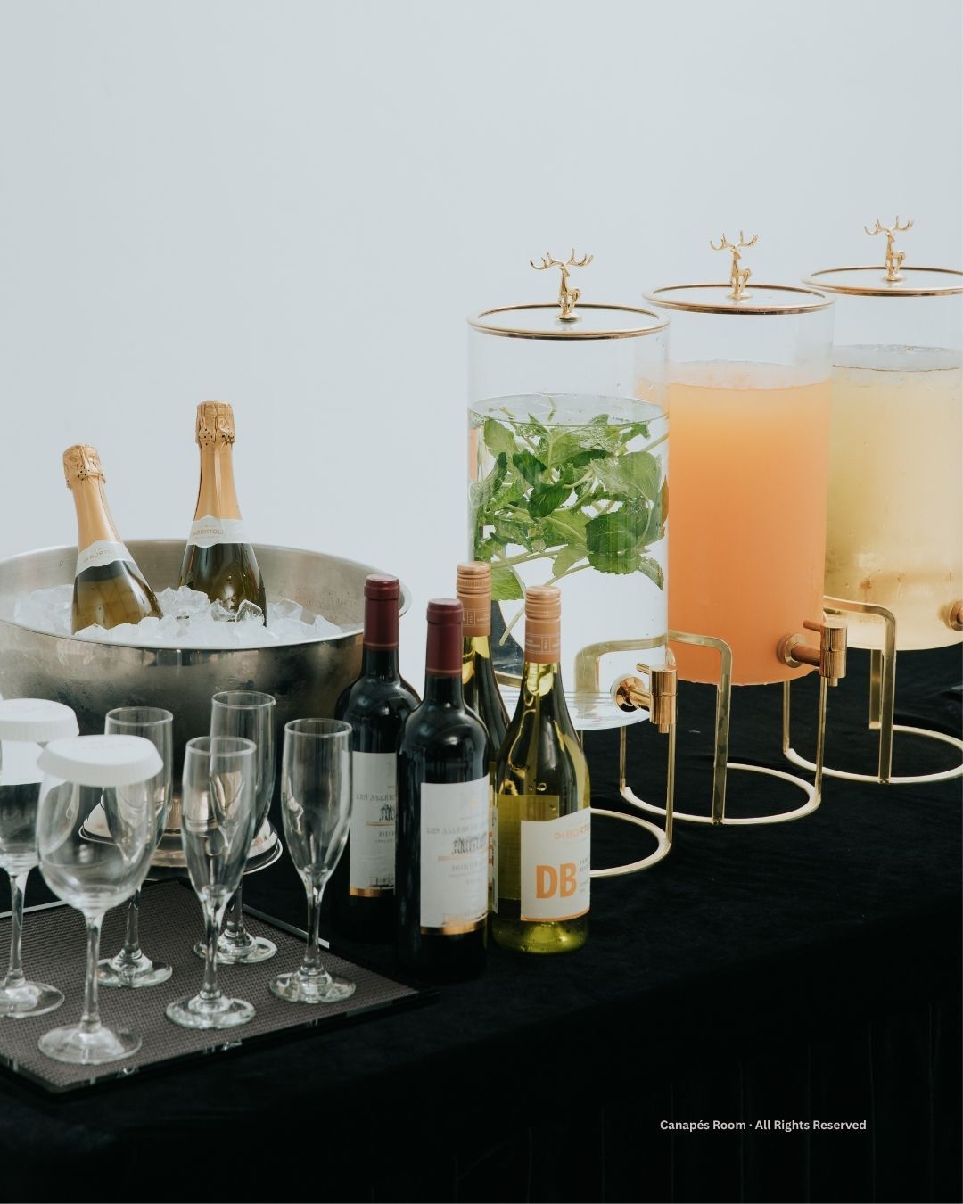 Person looking at a buffet of appetizers including sliders, and tarts under decorative lighting.