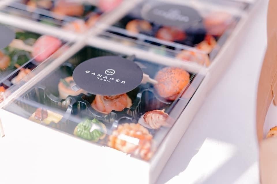 Box of assorted, colorful pastries with a black logo sticker.
