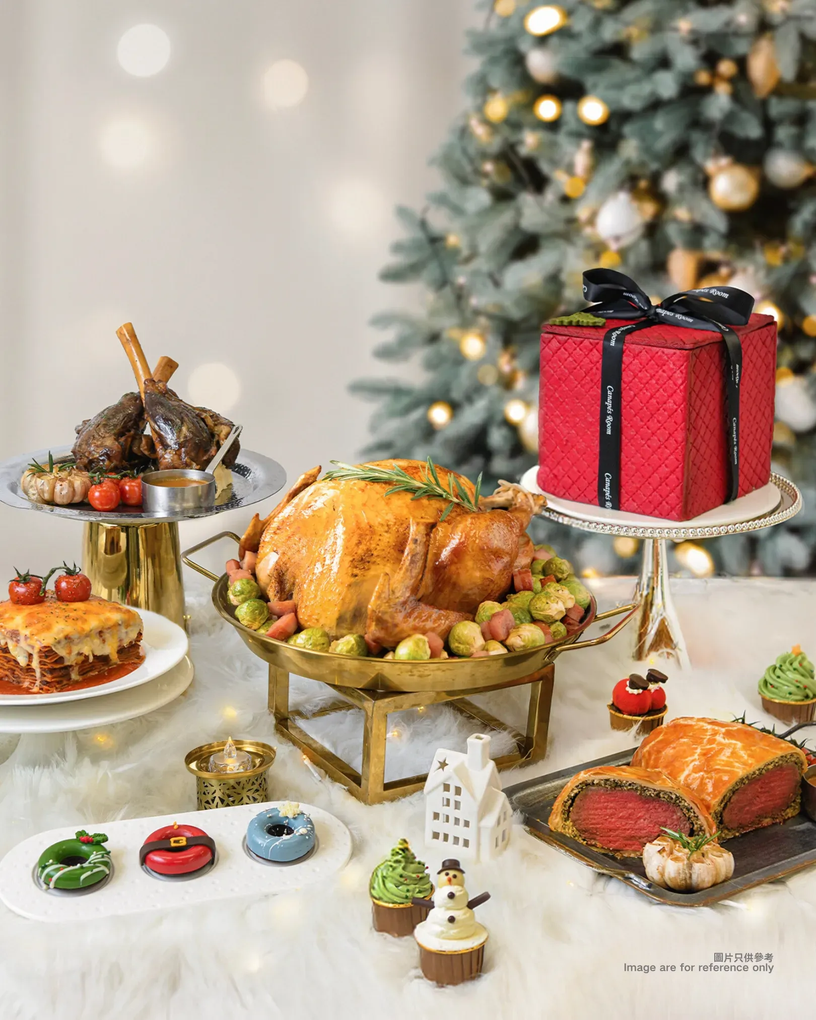 Christmas feast: turkey, lamb, cake, pastries, and cupcakes on a festive table with a tree in the background.