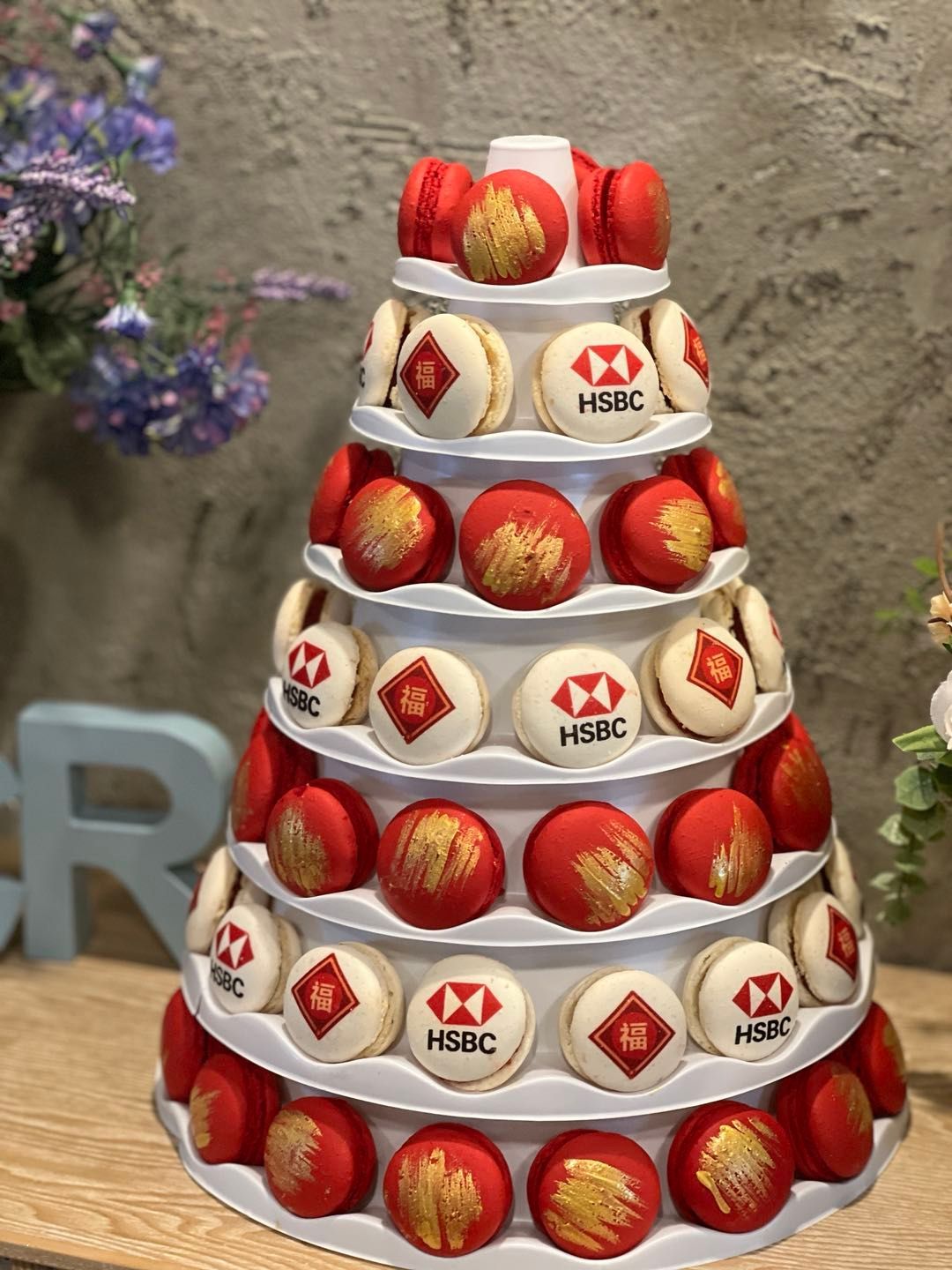 Macaron tower with red and white macarons, some with an HSBC logo and gold accents.