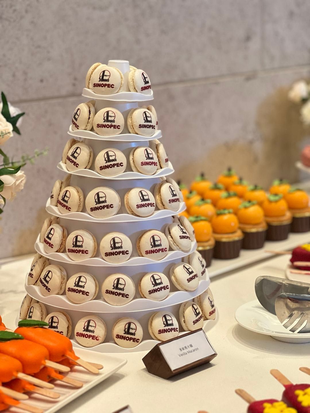 Pyramid of branded macarons on a dessert table; pumpkins, popsicles, and label present.