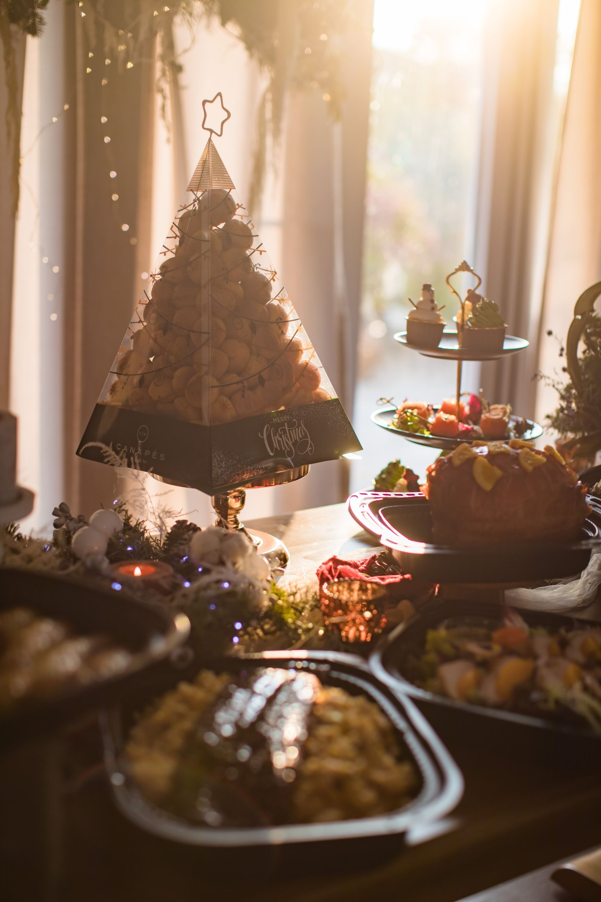 Christmas feast: a pyramid-shaped food tree, surrounded by dishes, sunlight streaming through a window.