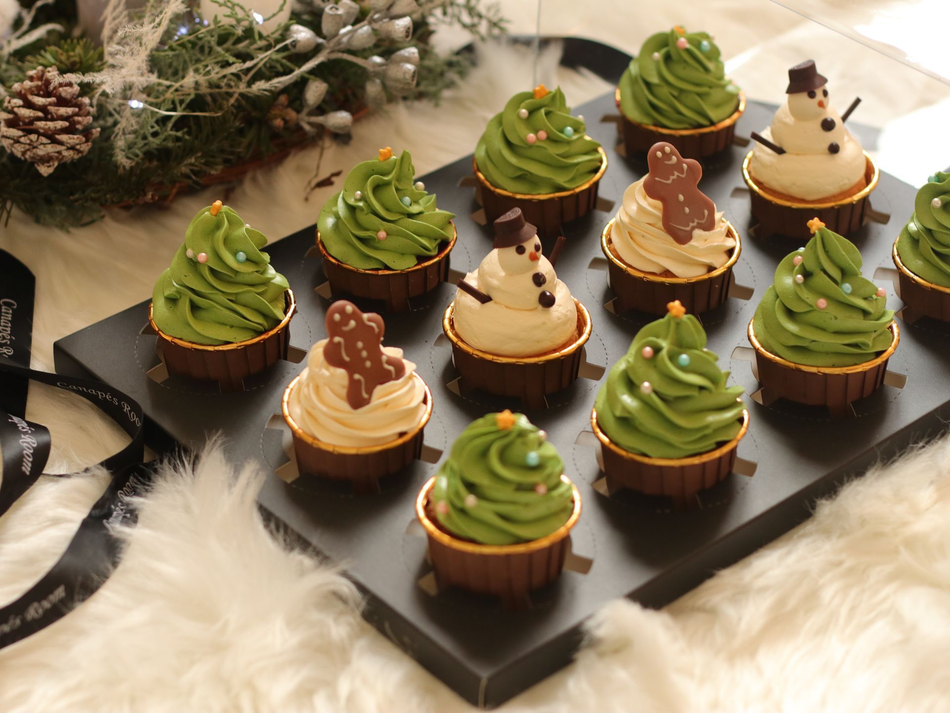 Christmas cupcakes, decorated with green frosting in tree shapes, gingerbread men, and snowman.