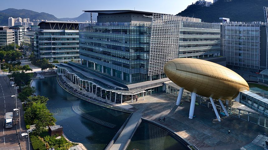 金色的蛋形建築矗立在現代玻璃建築群和橫跨水面的橋樑前，背靠巍峨的山脈。