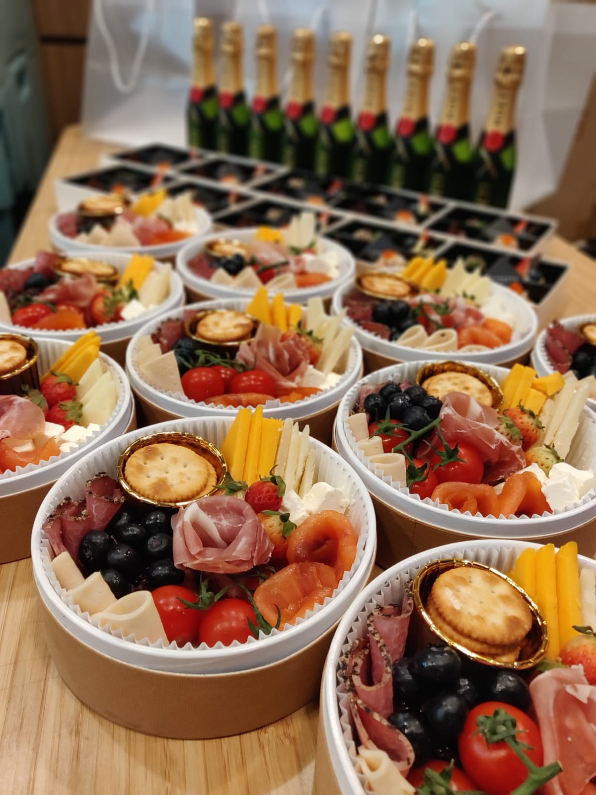 Individual charcuterie boxes, champagne bottles, and crackers.