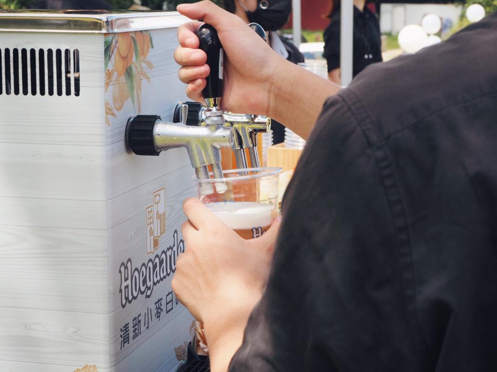 Person pouring beer from a tap into a glass outdoors.