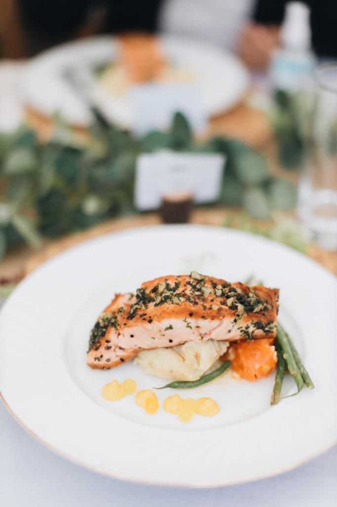 Salmon fillet with vegetables on a white plate.