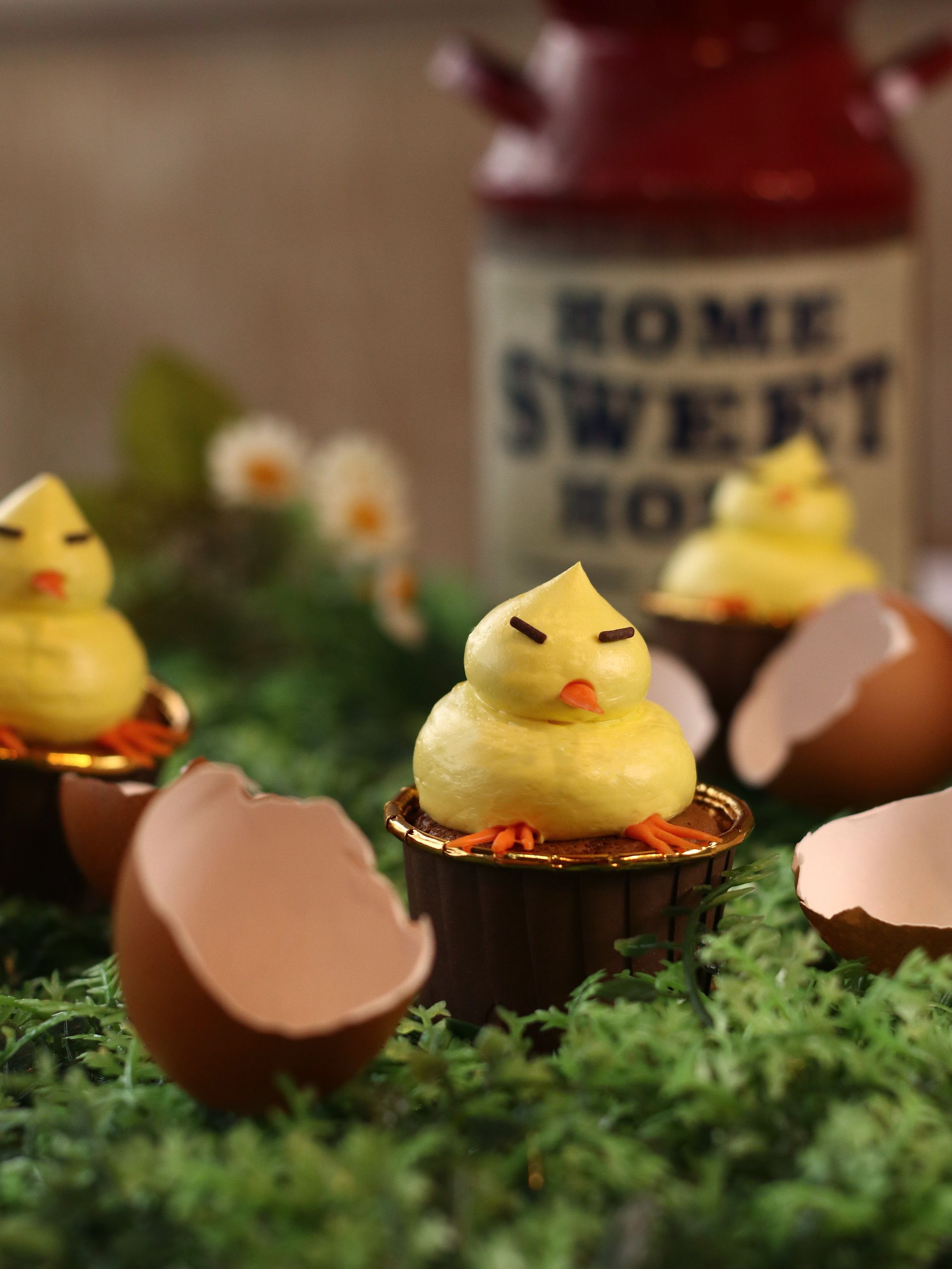 Yellow chick cupcakes in eggshell cups on moss with a
