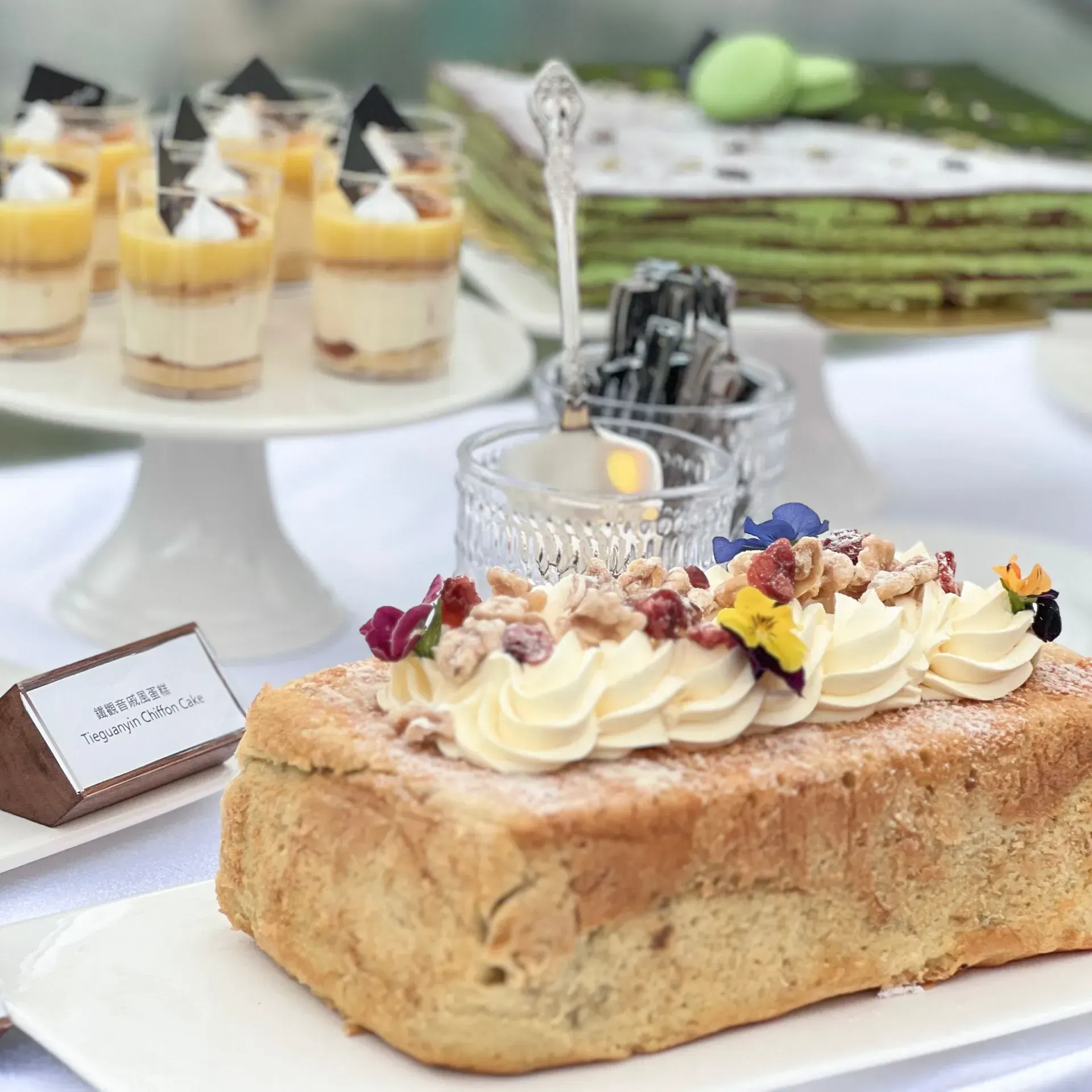 Dessert buffet: pound cake with frosting and nuts, layered crepe cake, parfaits, and sweets.