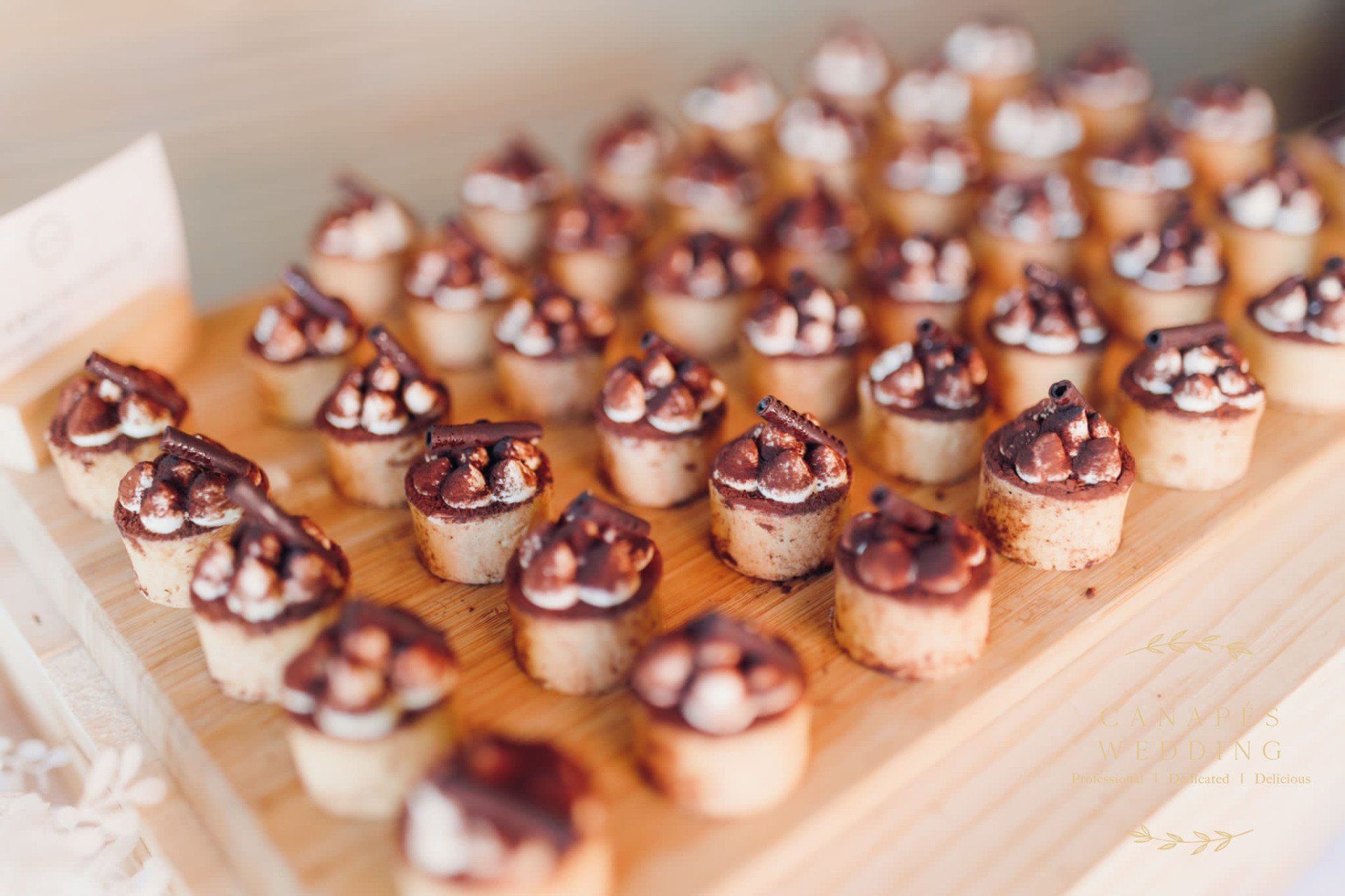 Miniature desserts on a wooden tray, topped with chocolate and marshmallows.
