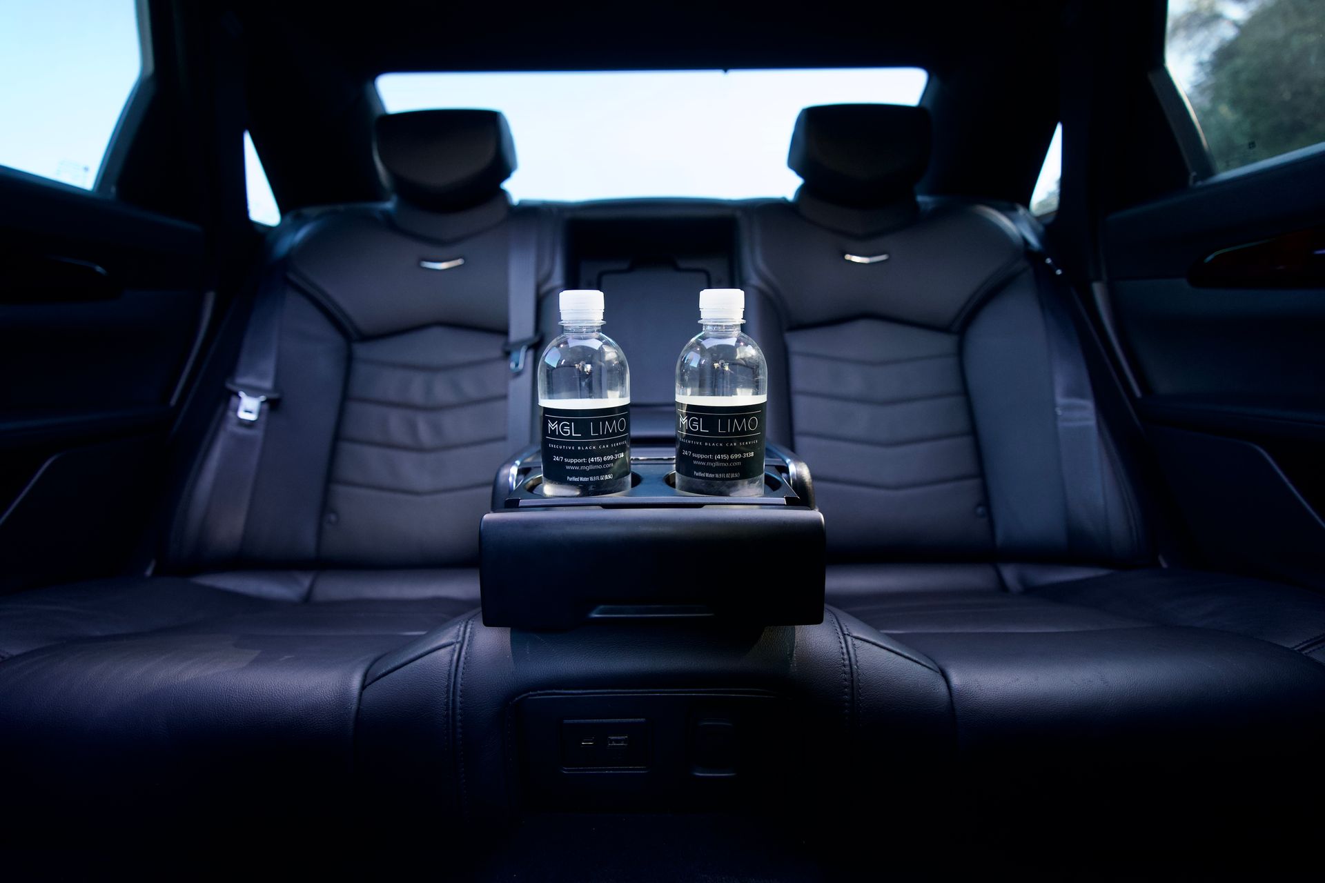 Interior car view: black leather seats, two water bottles in the center console.