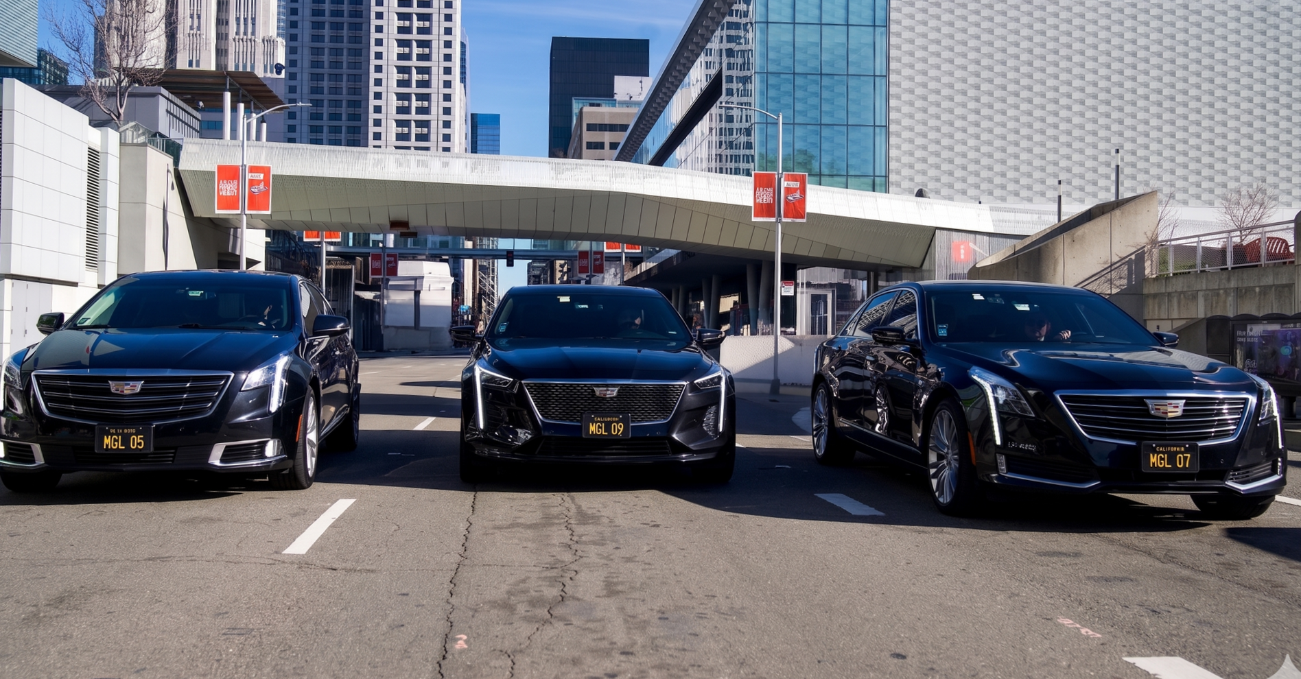 Three black cars parked side by side outdoors in front of San Francisco Moscone Center.