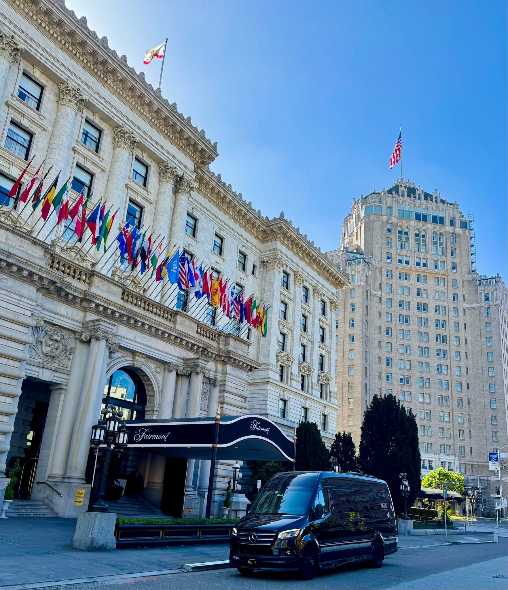 MGL Limo Mercedes‑Sprinter vans parked in front of the Fairmont San Francisco hotel, professional.