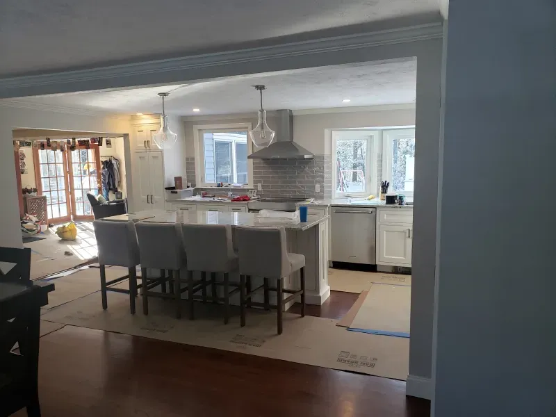Kitchen renovation: open layout with island, bar stools, and white cabinetry.