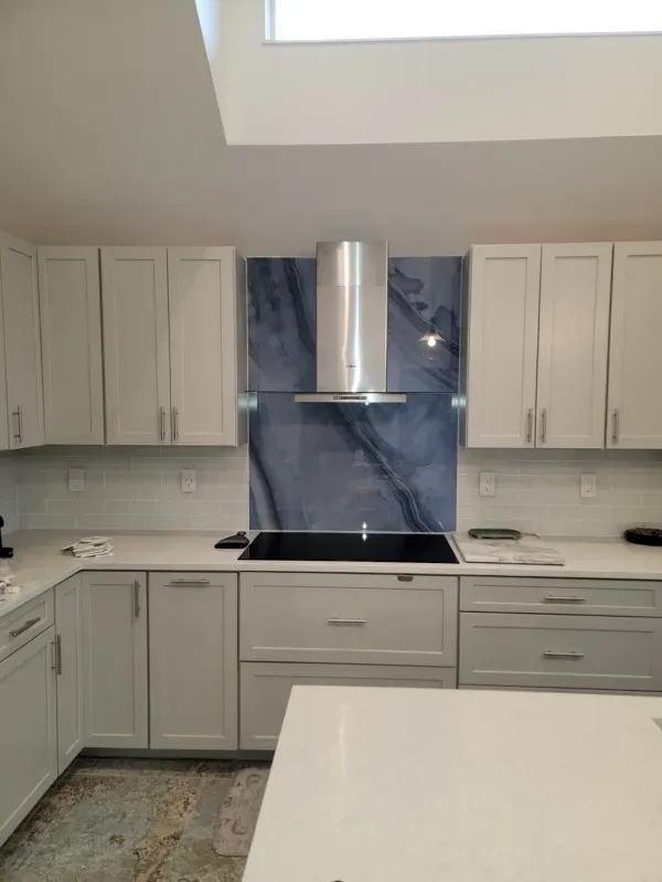Modern kitchen with white cabinets, blue marble backsplash, and stainless steel range hood.