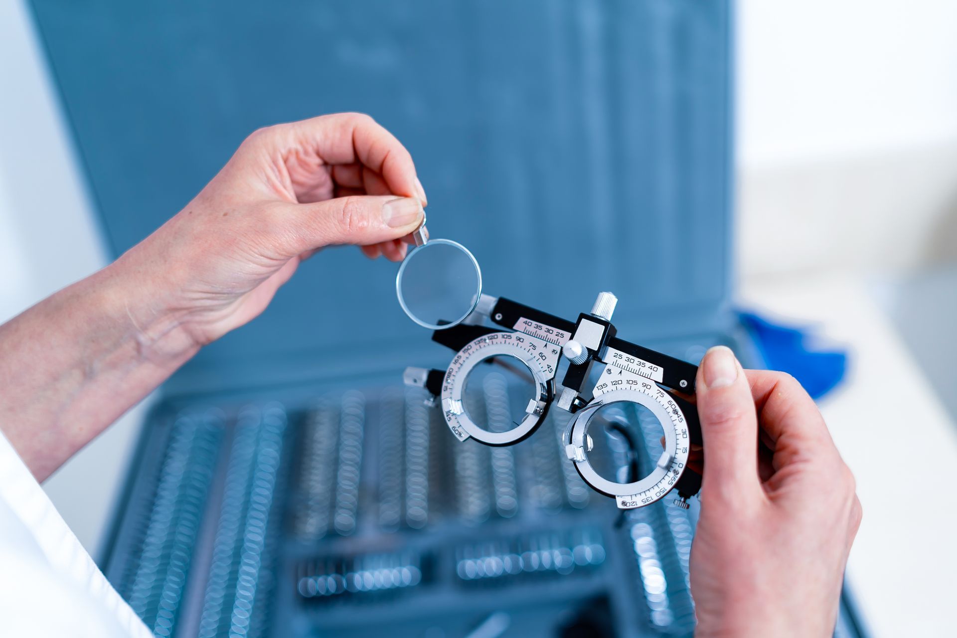 Hands holding a phoropter lens device in a clinical setting