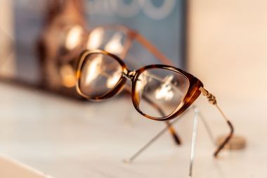 Tortoiseshell eyeglasses on a wooden surface, softly lit and in focus