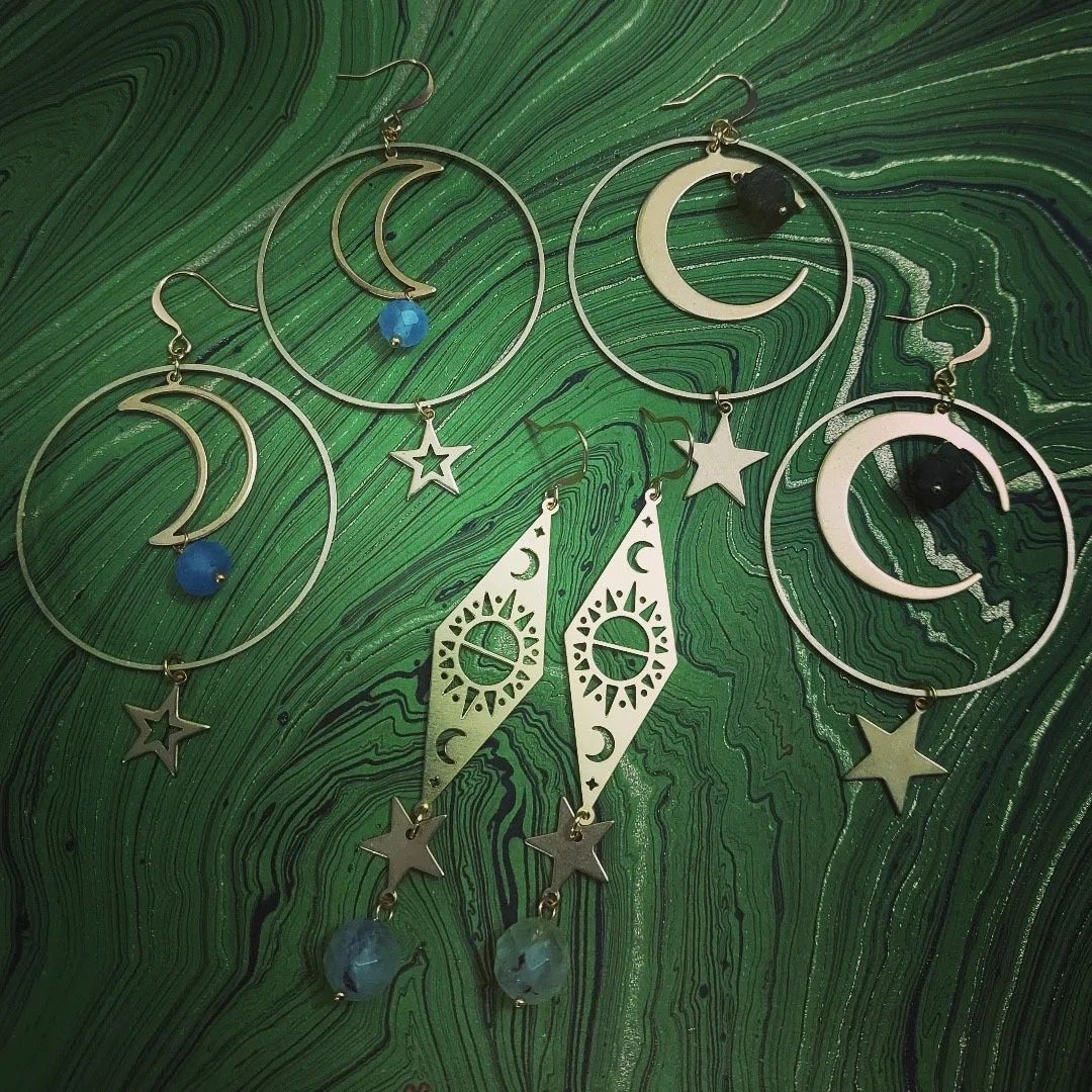 Silver moon and star earrings with blue beads on a dark green marbled background