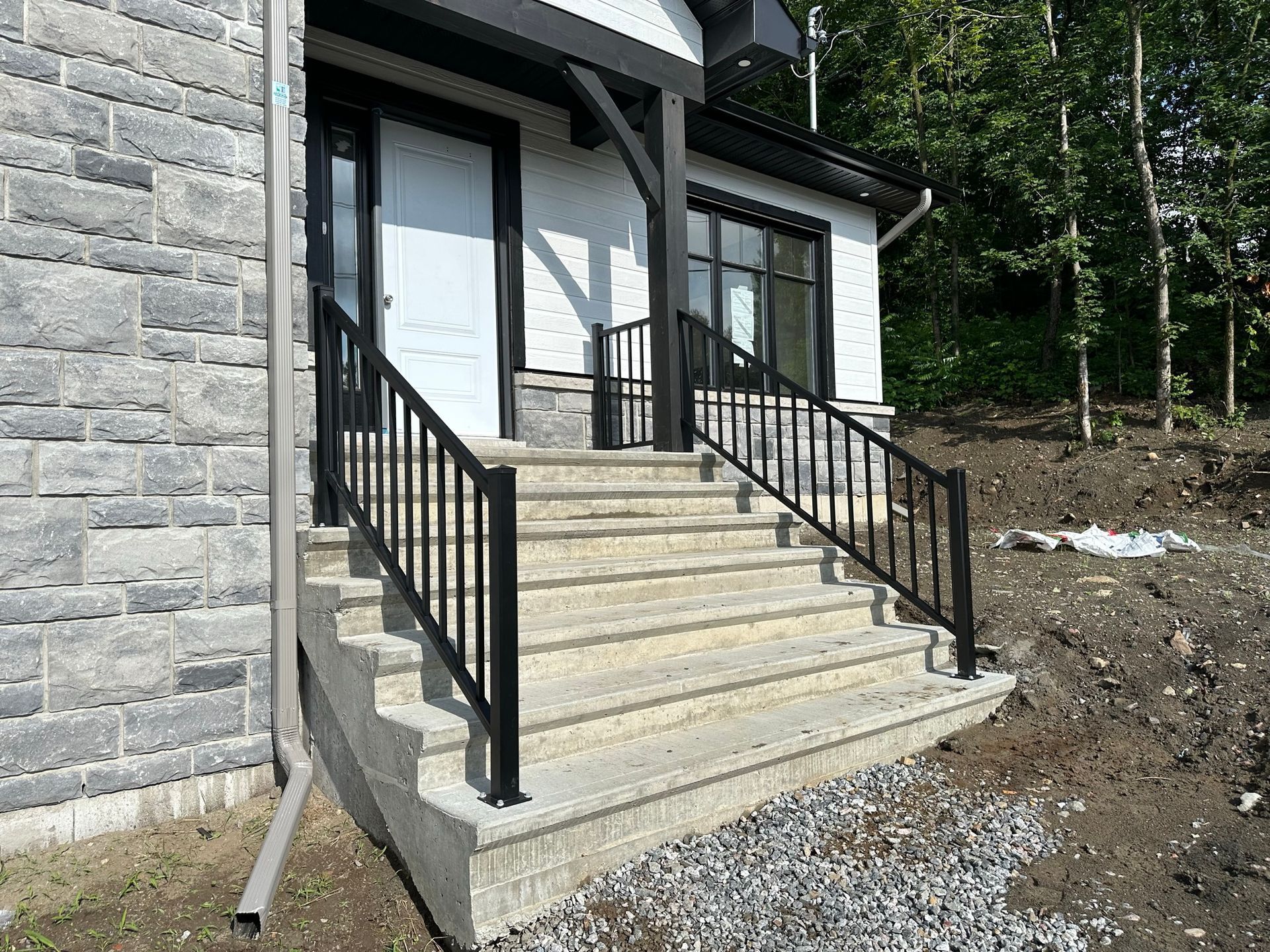 Un escalier menant à une maison avec une rampe noire.