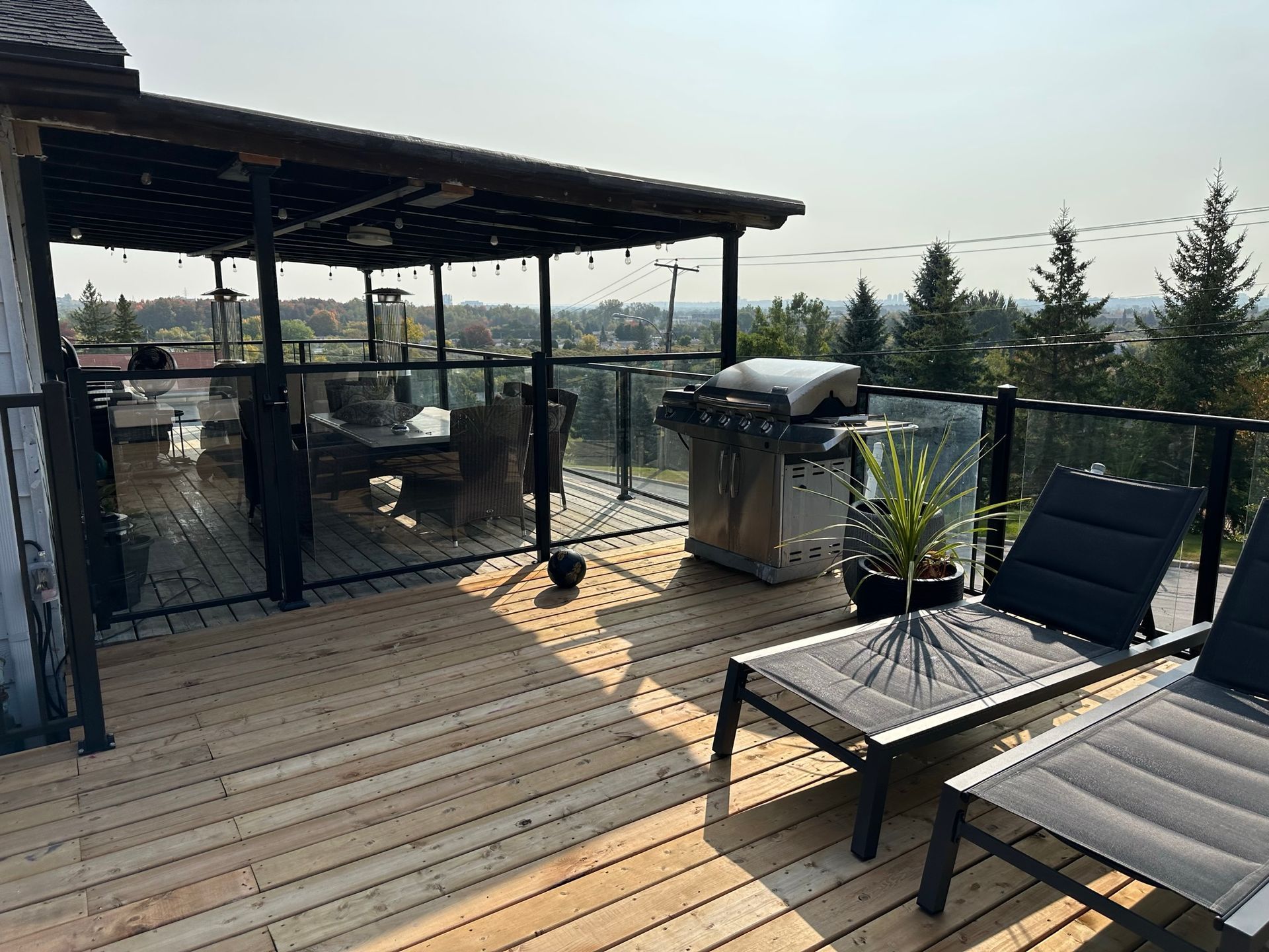 Une terrasse en bois avec un barbecue et des chaises dessus.