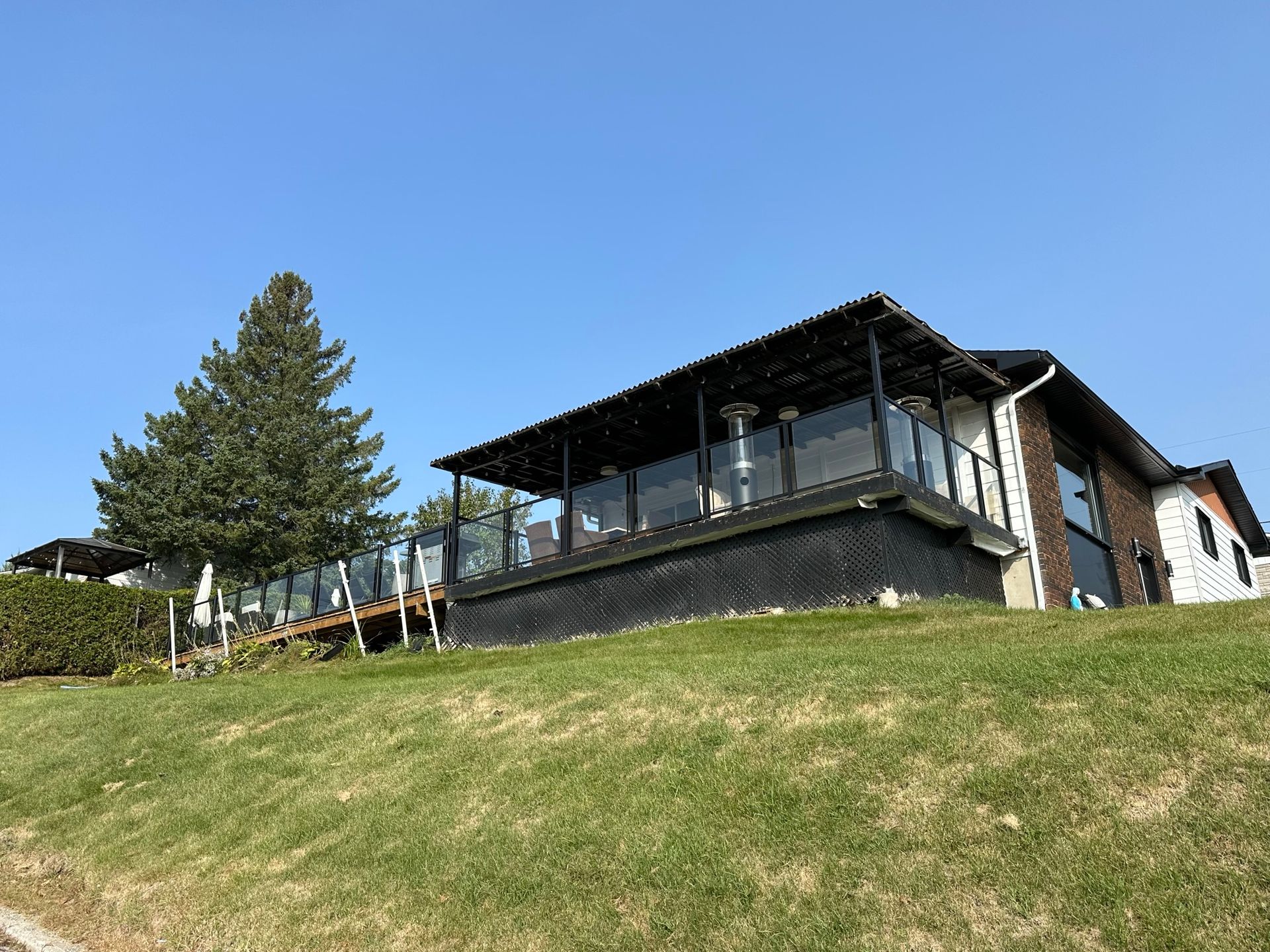 Une grande maison est située au sommet d'une colline herbeuse.