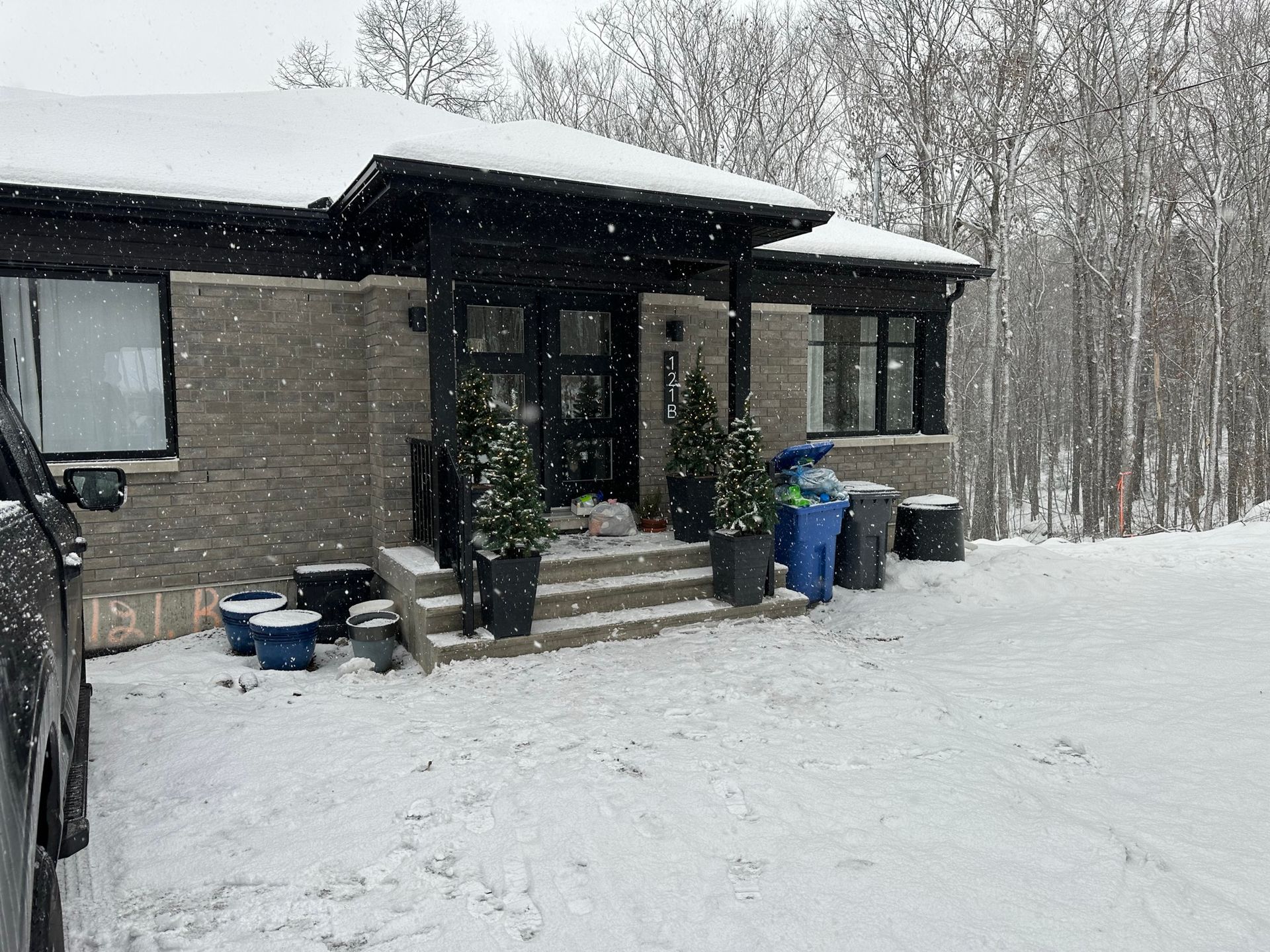 Une maison est couverte de neige et une voiture est garée devant elle.