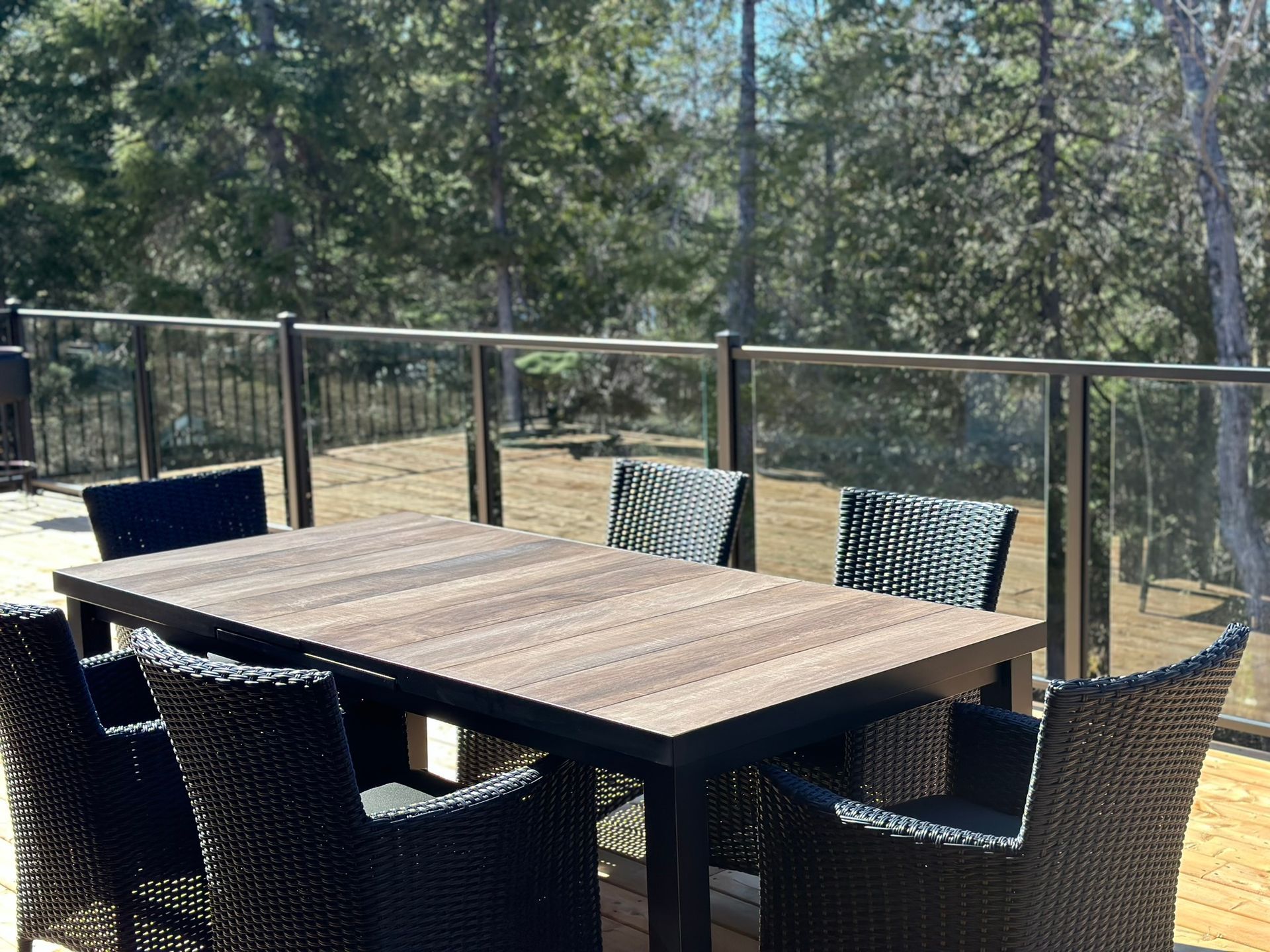 Une table et des chaises en bois sur une terrasse avec des arbres en arrière-plan