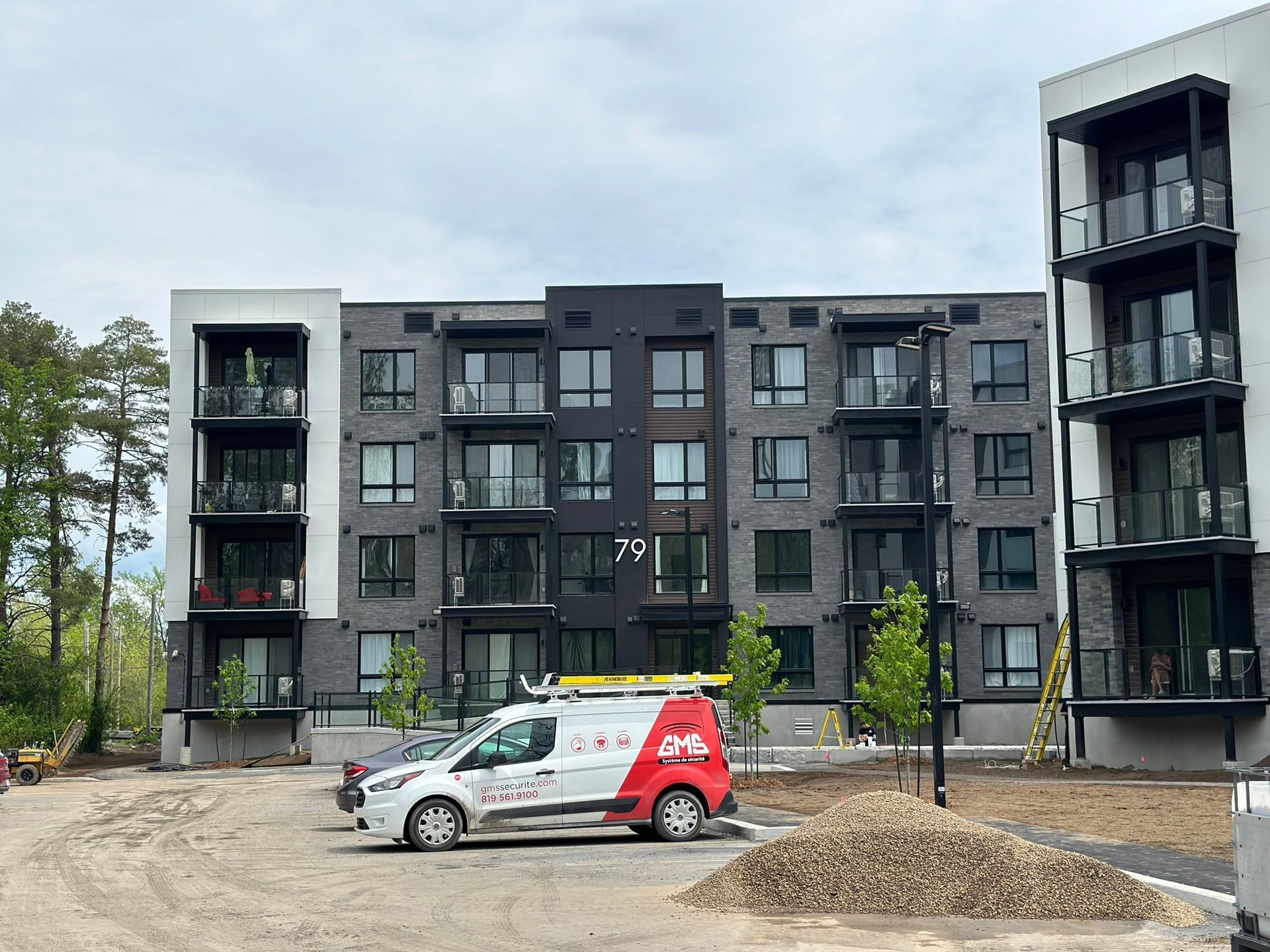 Une camionnette est garée devant un grand immeuble d'appartements.