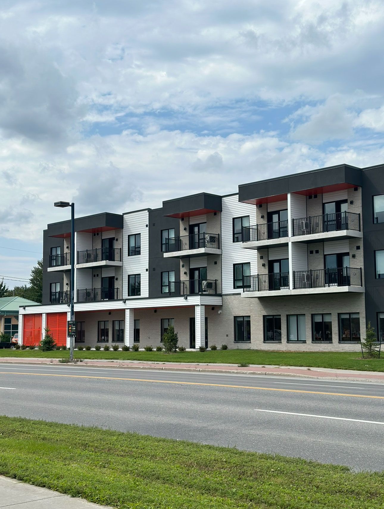 Un grand immeuble d'appartements avec beaucoup de fenêtres se trouve à côté d'une rue.