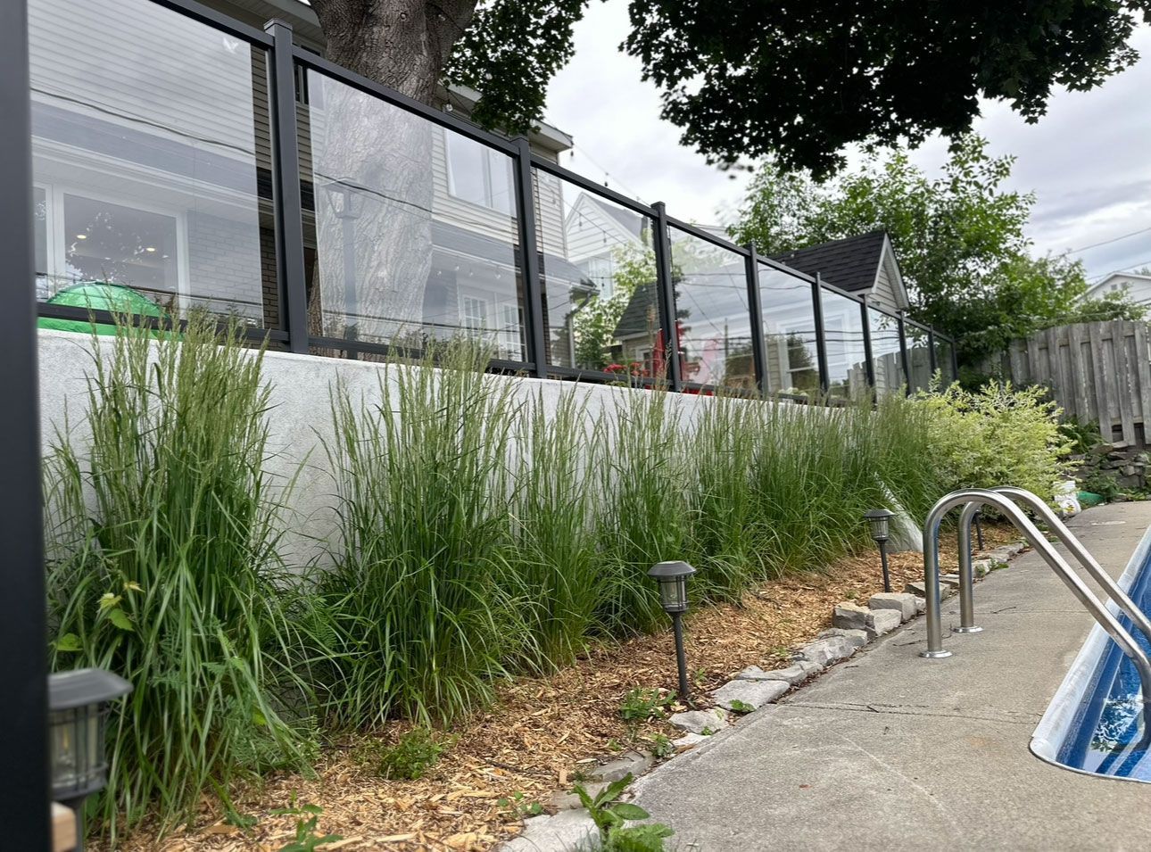 Une clôture entoure une piscine dans une cour arrière.