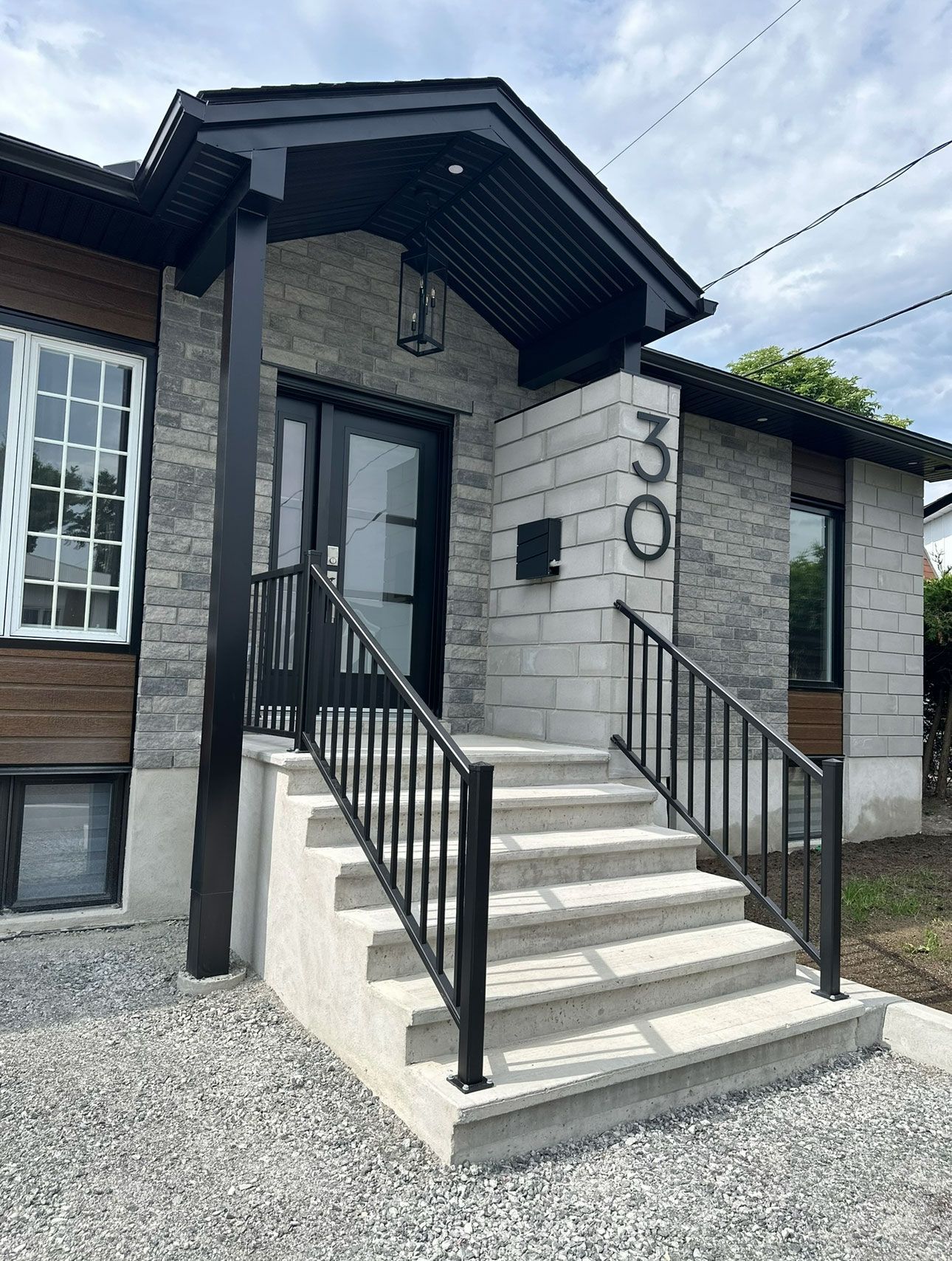 Une maison avec des escaliers menant à la porte d'entrée et une balustrade noire.
