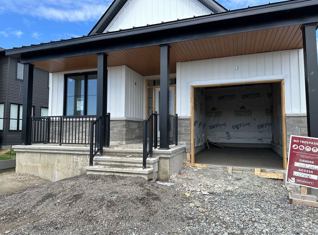 Une maison est en construction avec un garage et un porche.