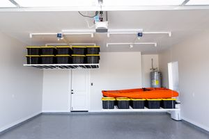 Garage interior with wall-mounted storage bins, orange kayak, and ceiling storage rack