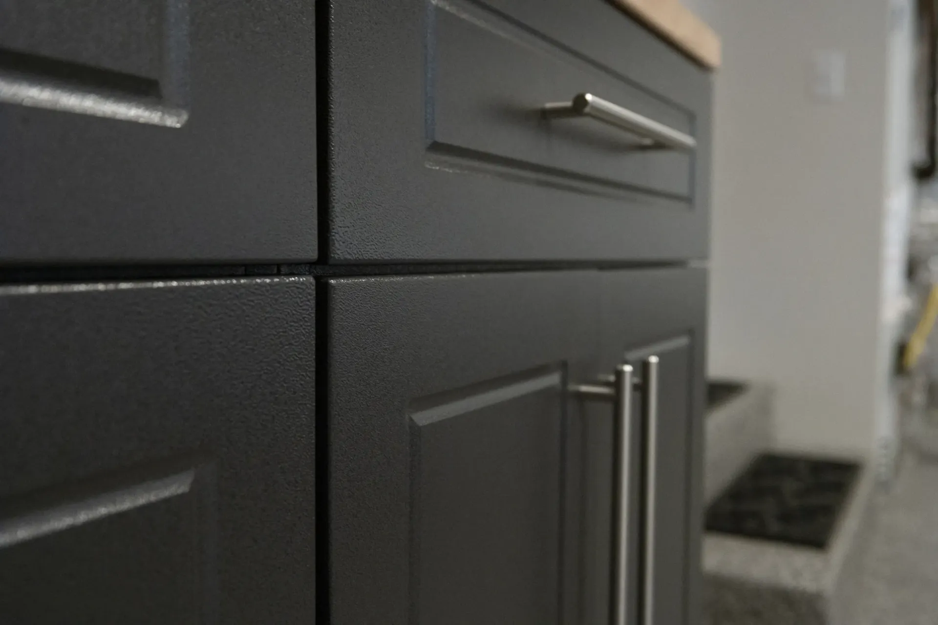 Close-up of dark gray kitchen cabinets with silver handles along a hallway