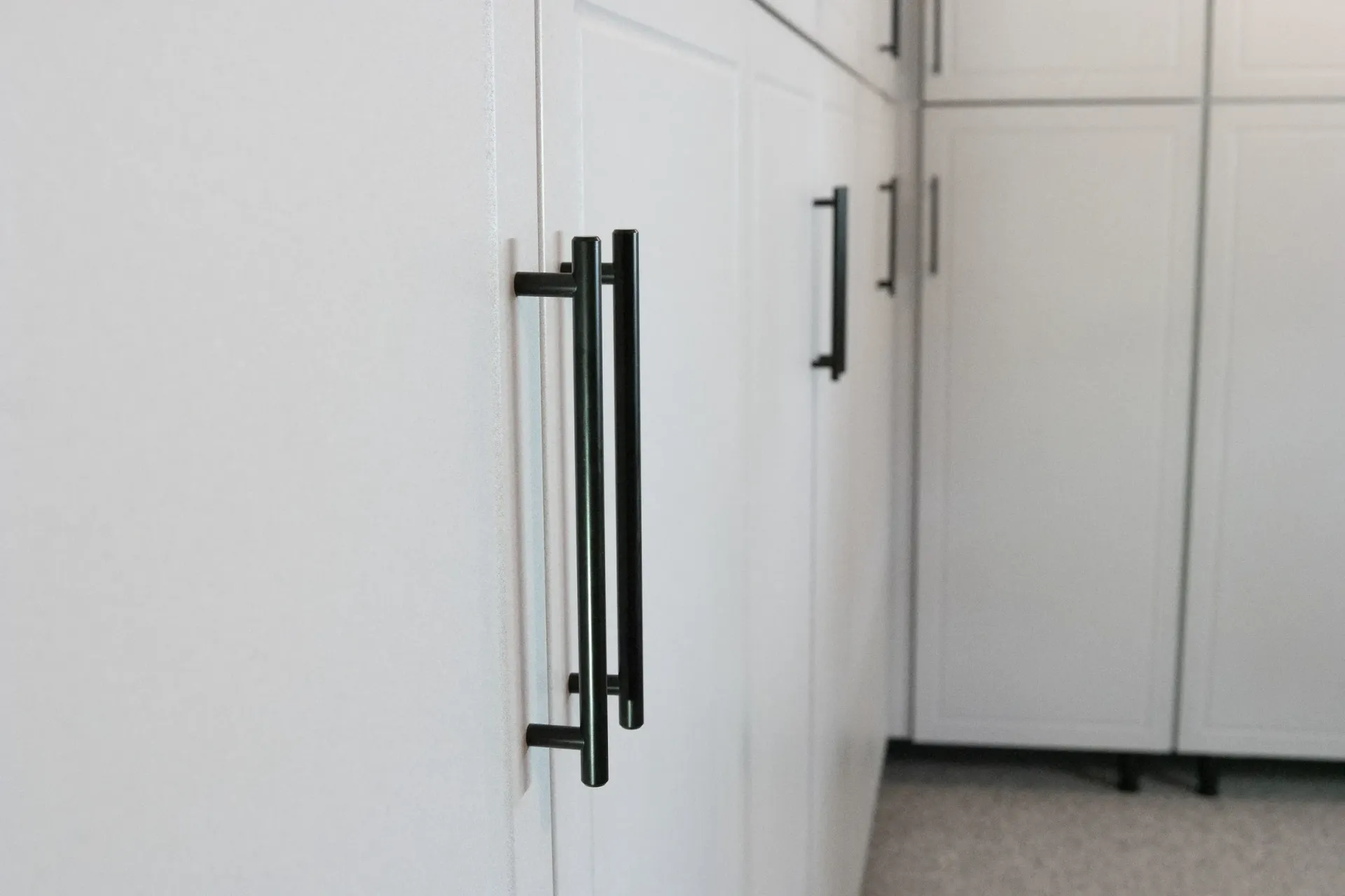 White kitchen cabinets with black handles in a clean, modern room