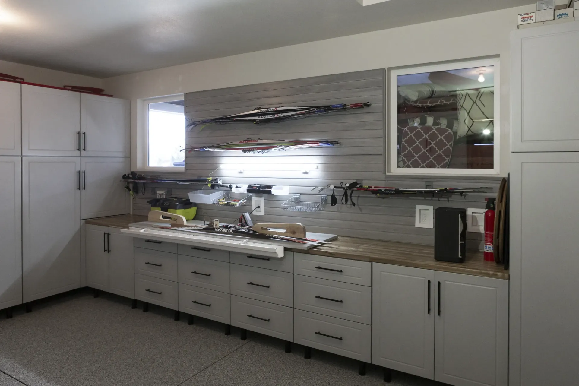 Modern white kitchen with long countertops, cabinets, sink, and red accents in a tidy interior