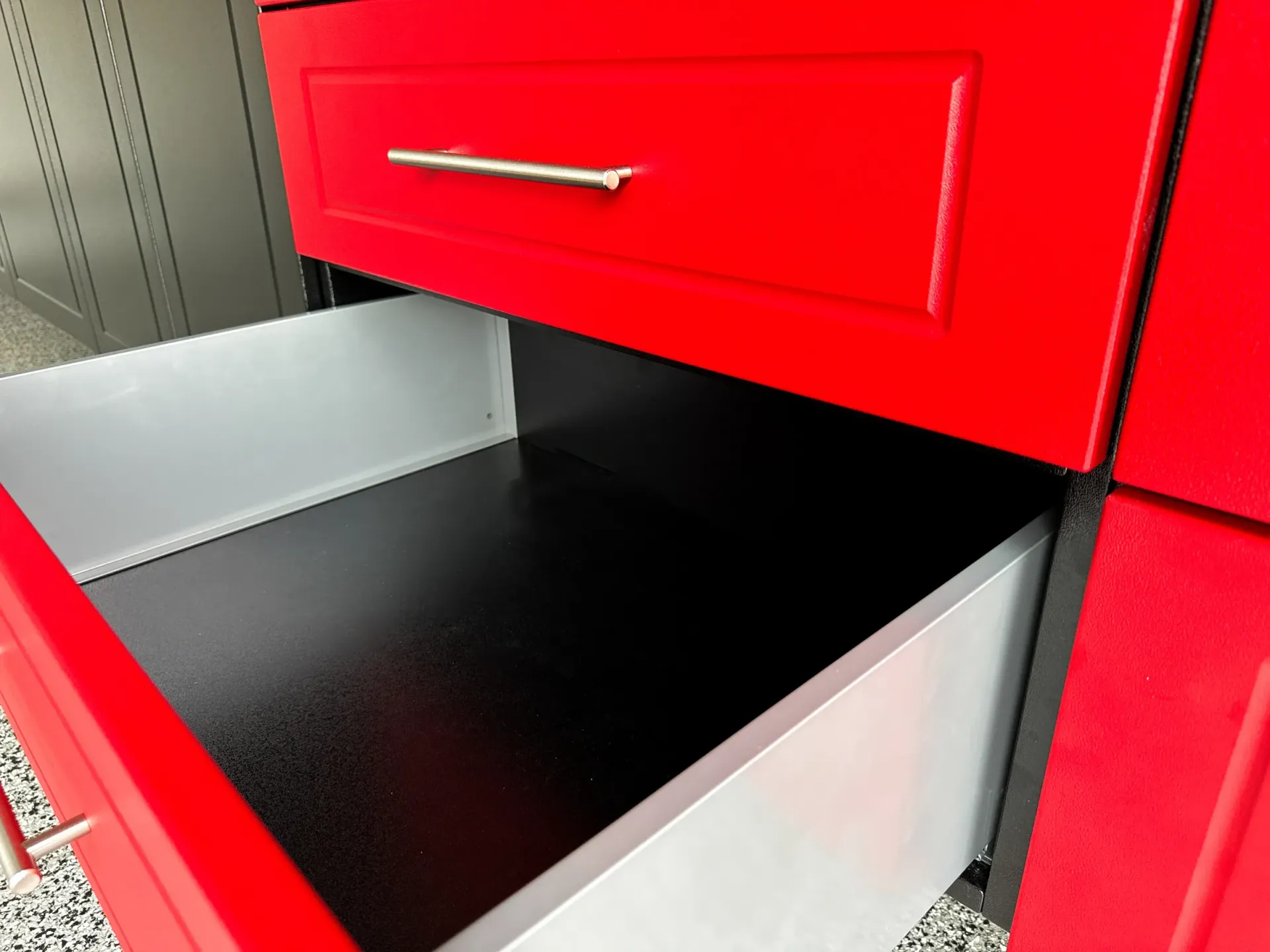 Red cabinet drawer open above a black countertop in a kitchen or utility area.