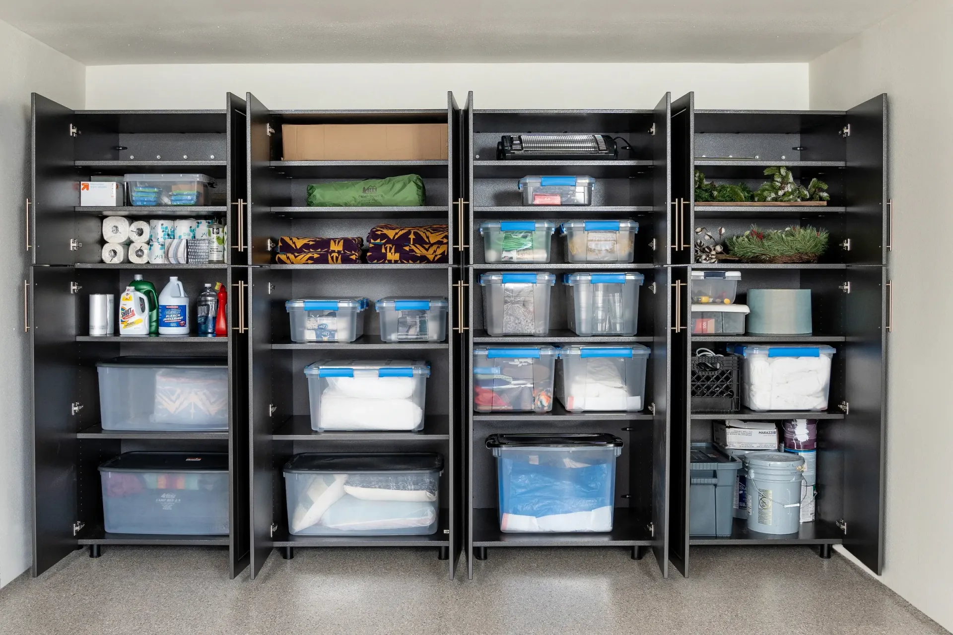 Open storage cabinet with labeled bins, containers, and household supplies organized on shelves
