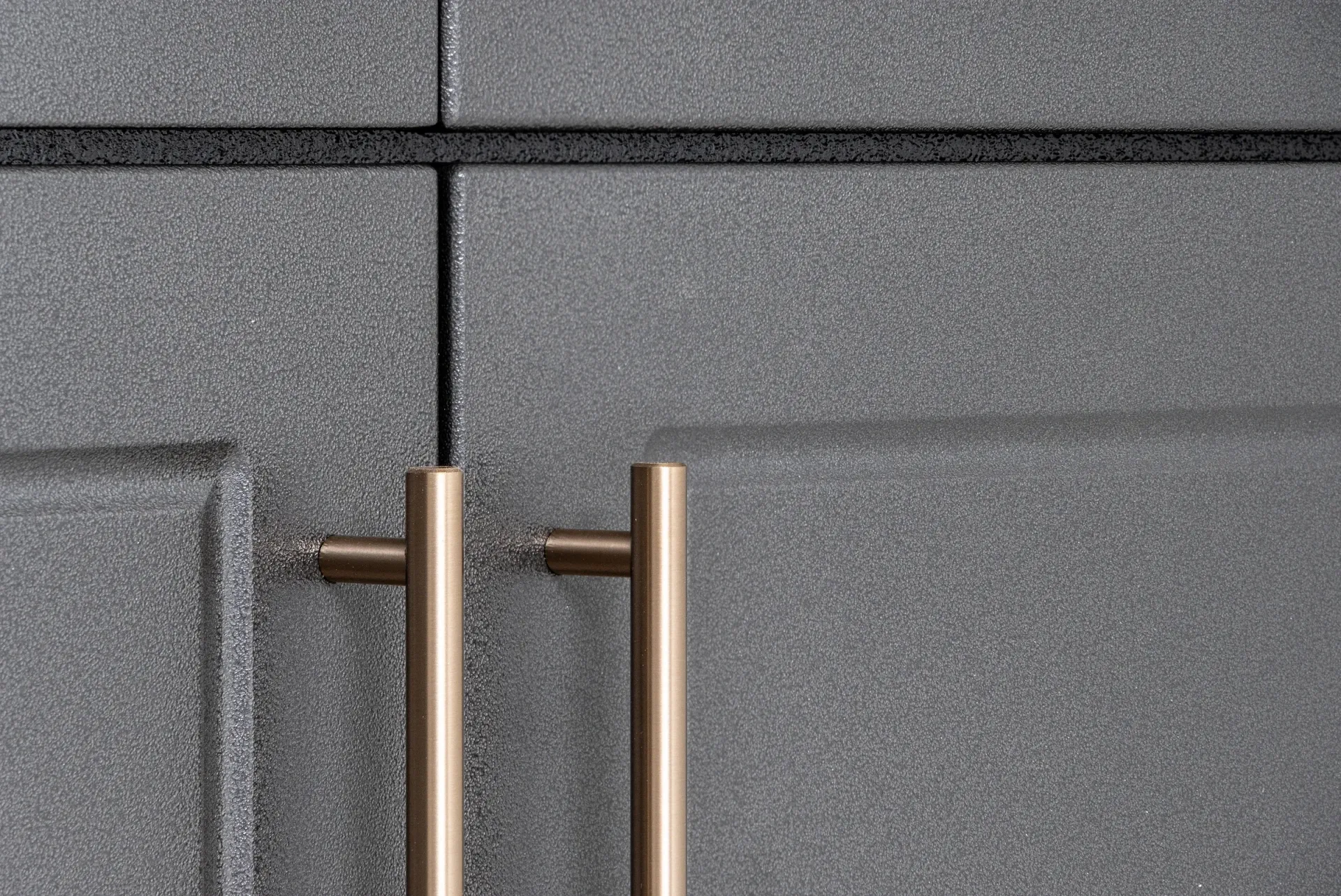 Two brass cabinet pulls on a gray speckled cabinet door, centered on the seam.