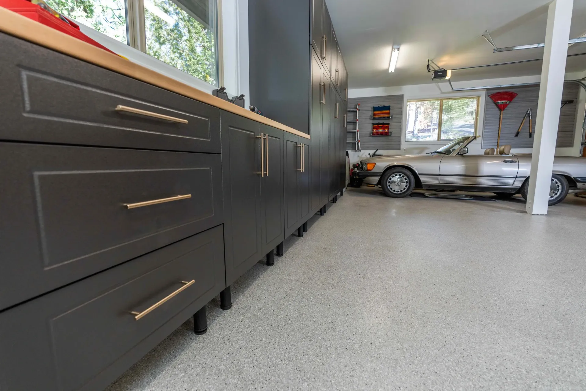 Modern garage interior with black cabinets, silver car, and speckled epoxy floor