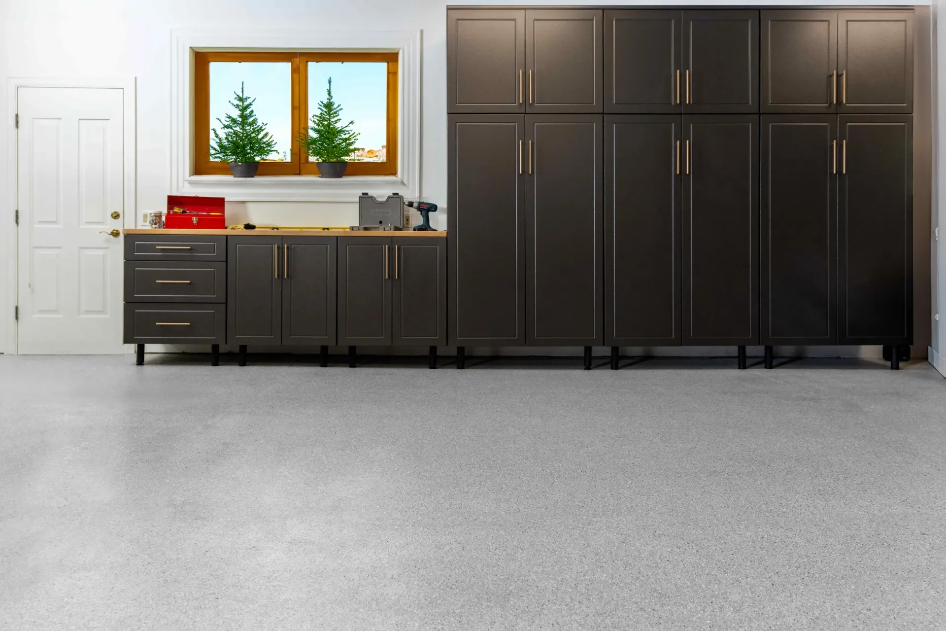 Modern garage with dark cabinets, a window, and a gray speckled floor